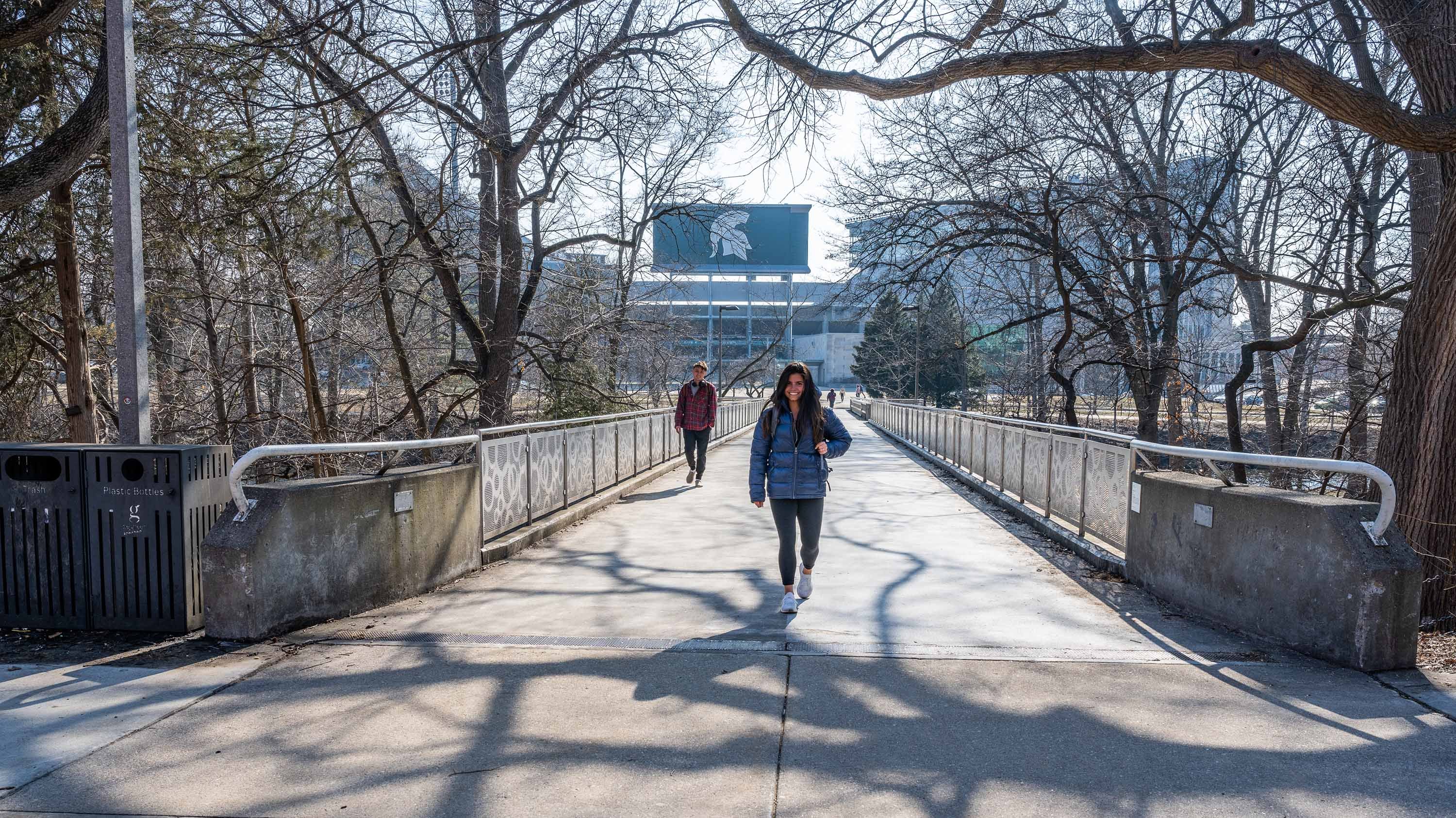 Students walking across MSU library bridge