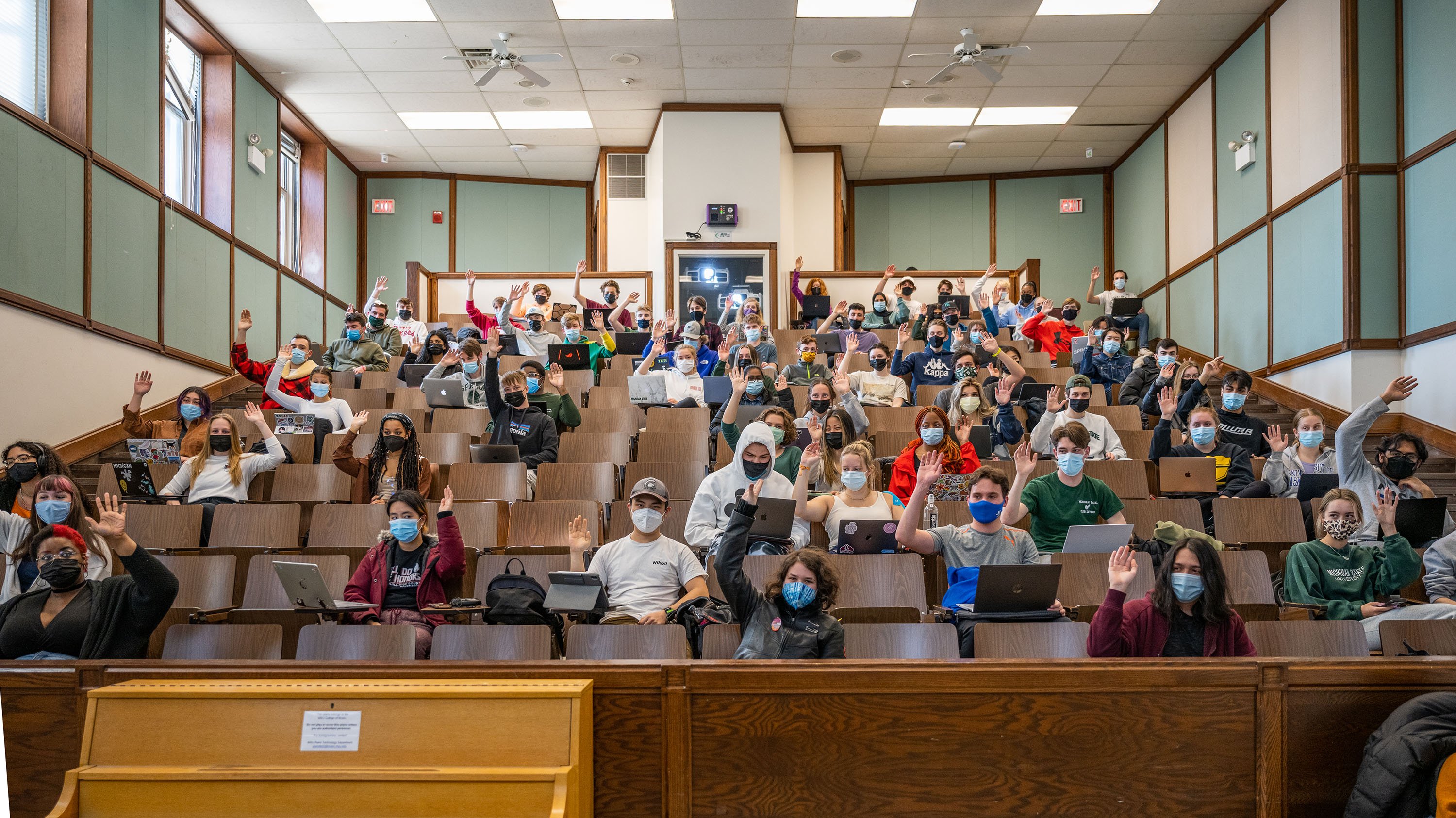 Students in lecture hall, some with hands raised