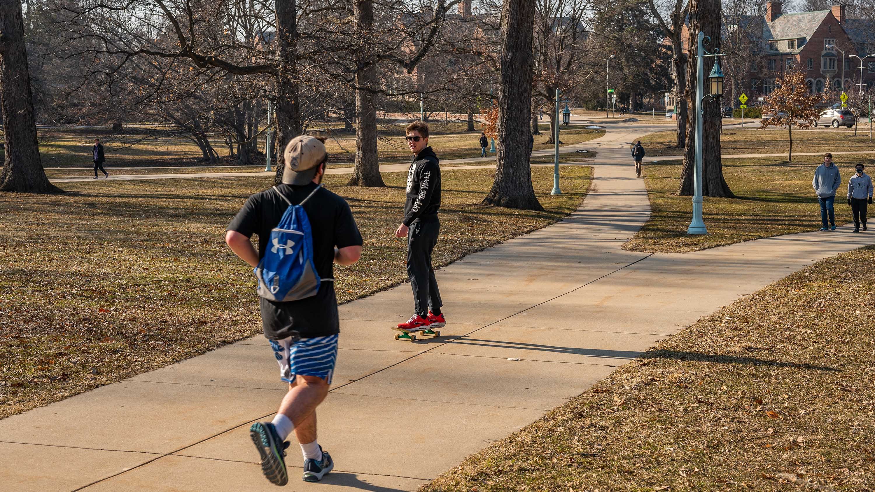 Skateboarder and students walking on campus
