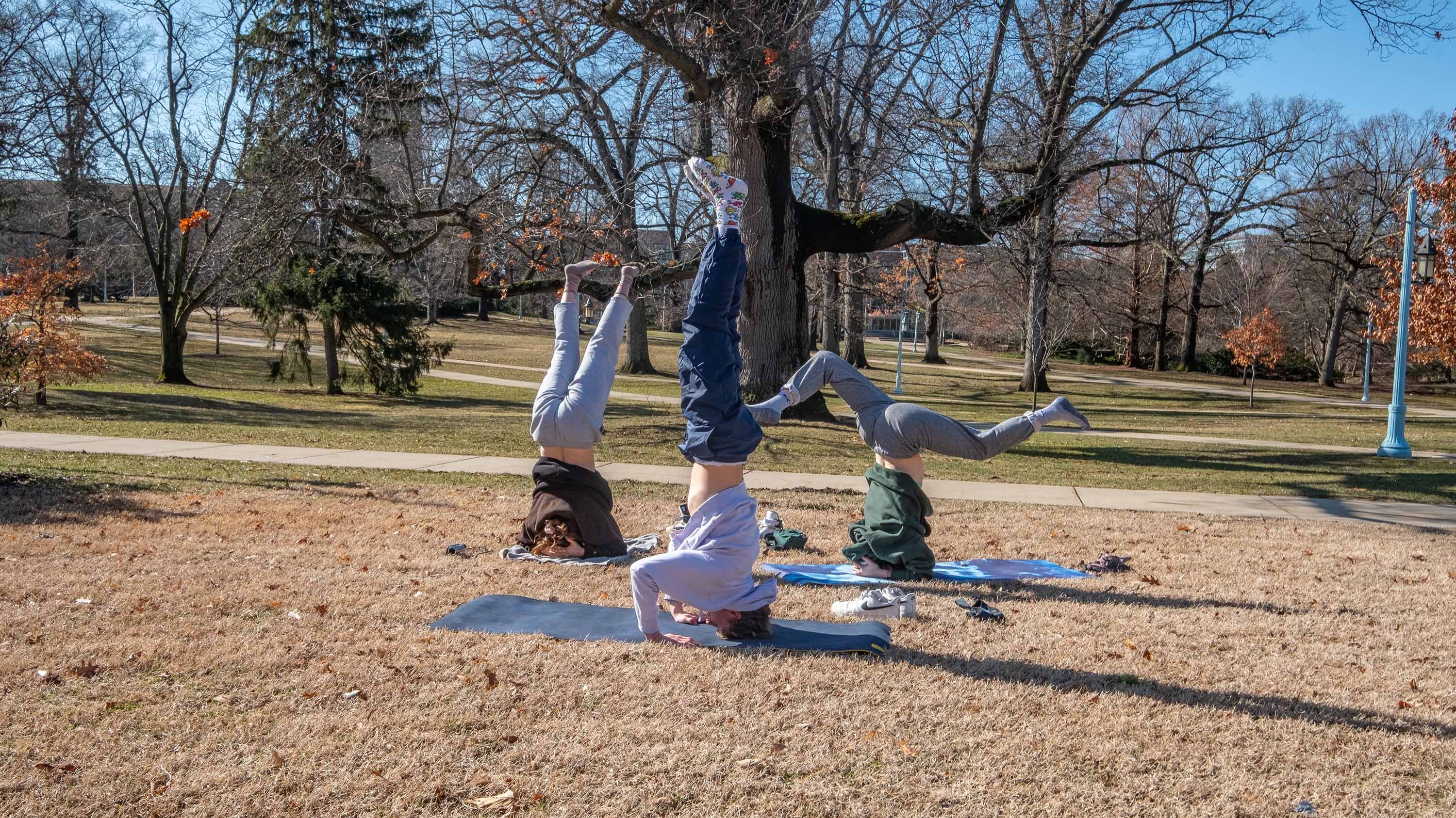 Three students doing yoga outdoors