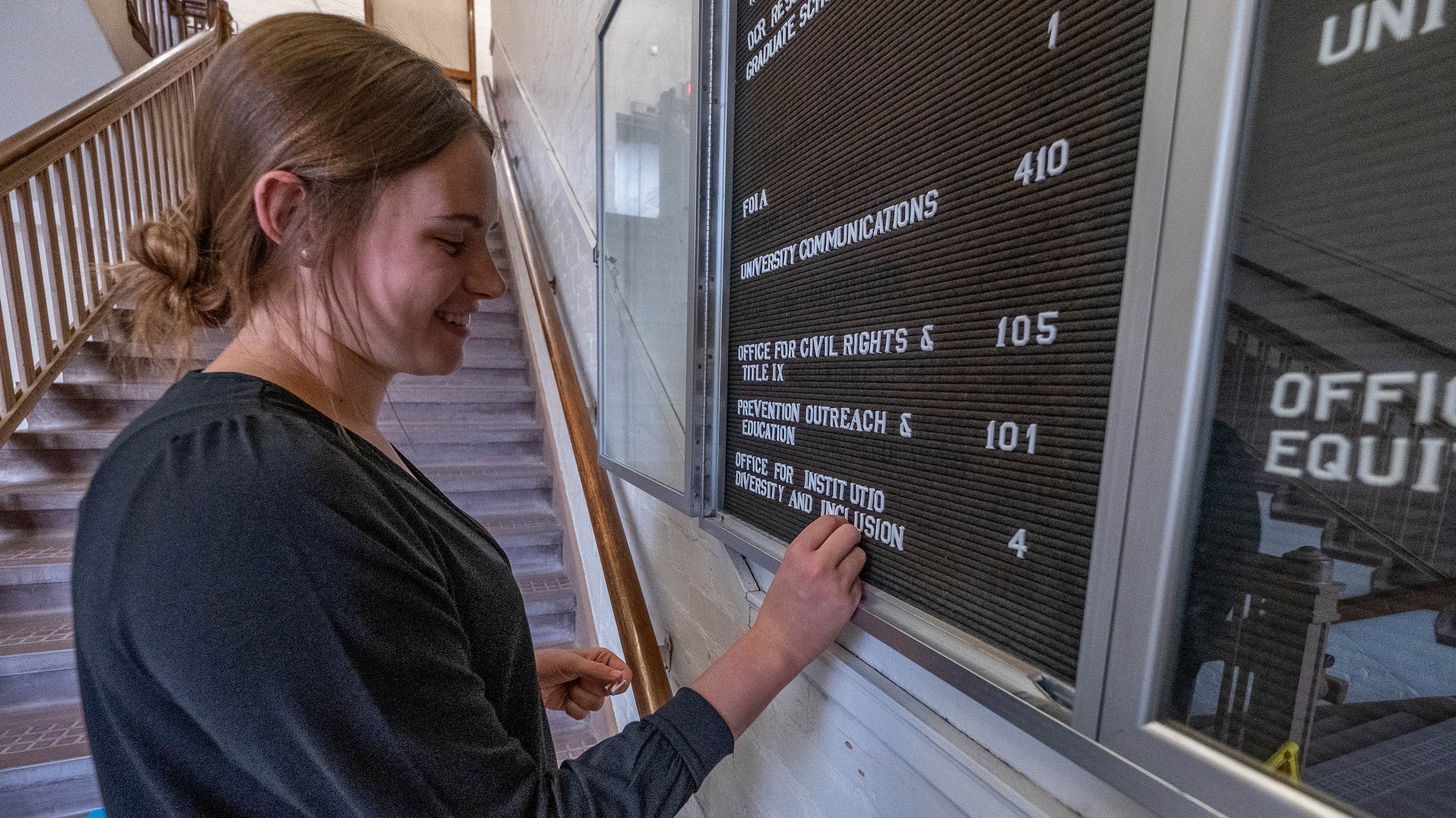 Student changing out letters on a directory board