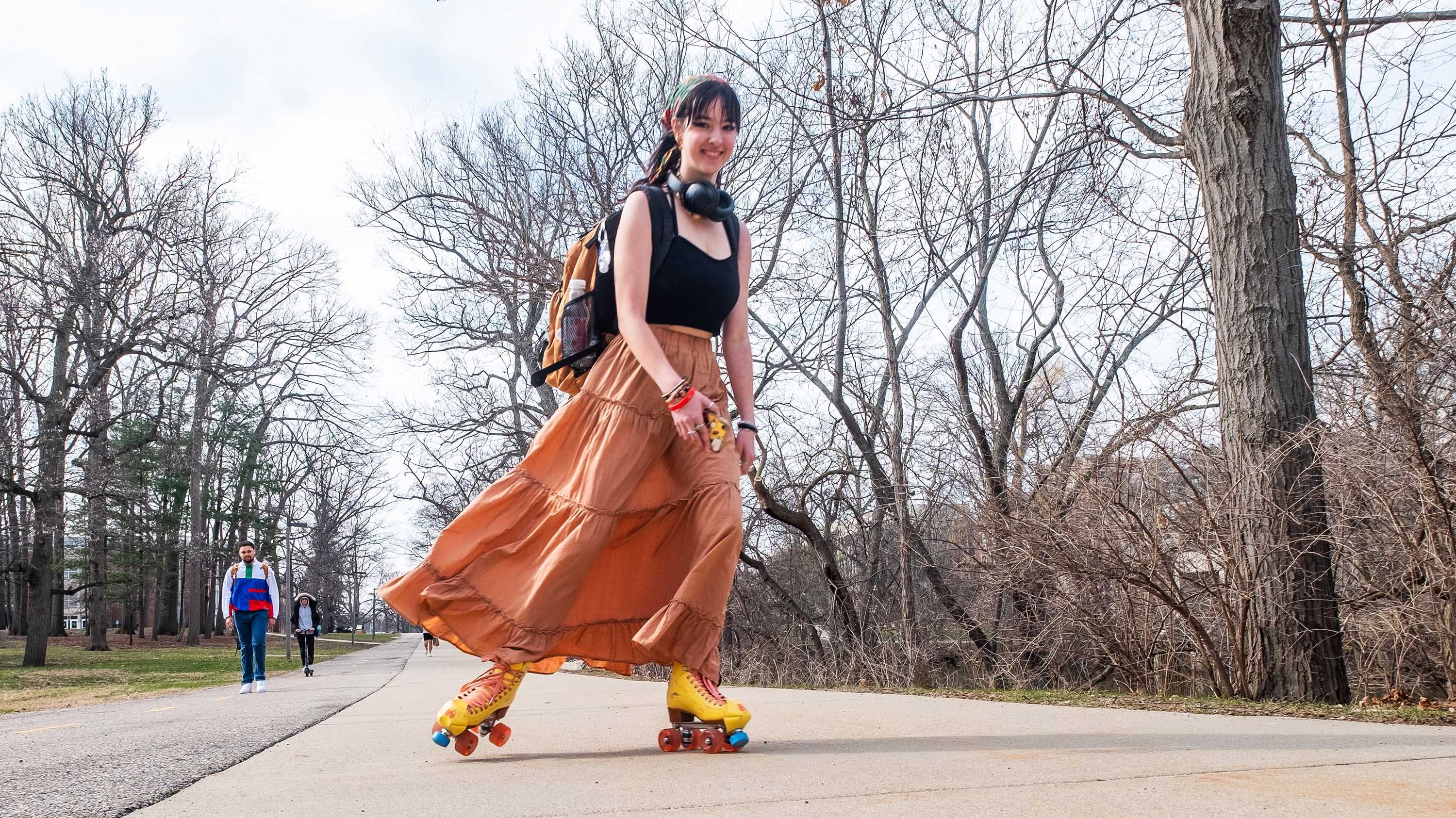 Person roller skating on campus near Red Cedar river