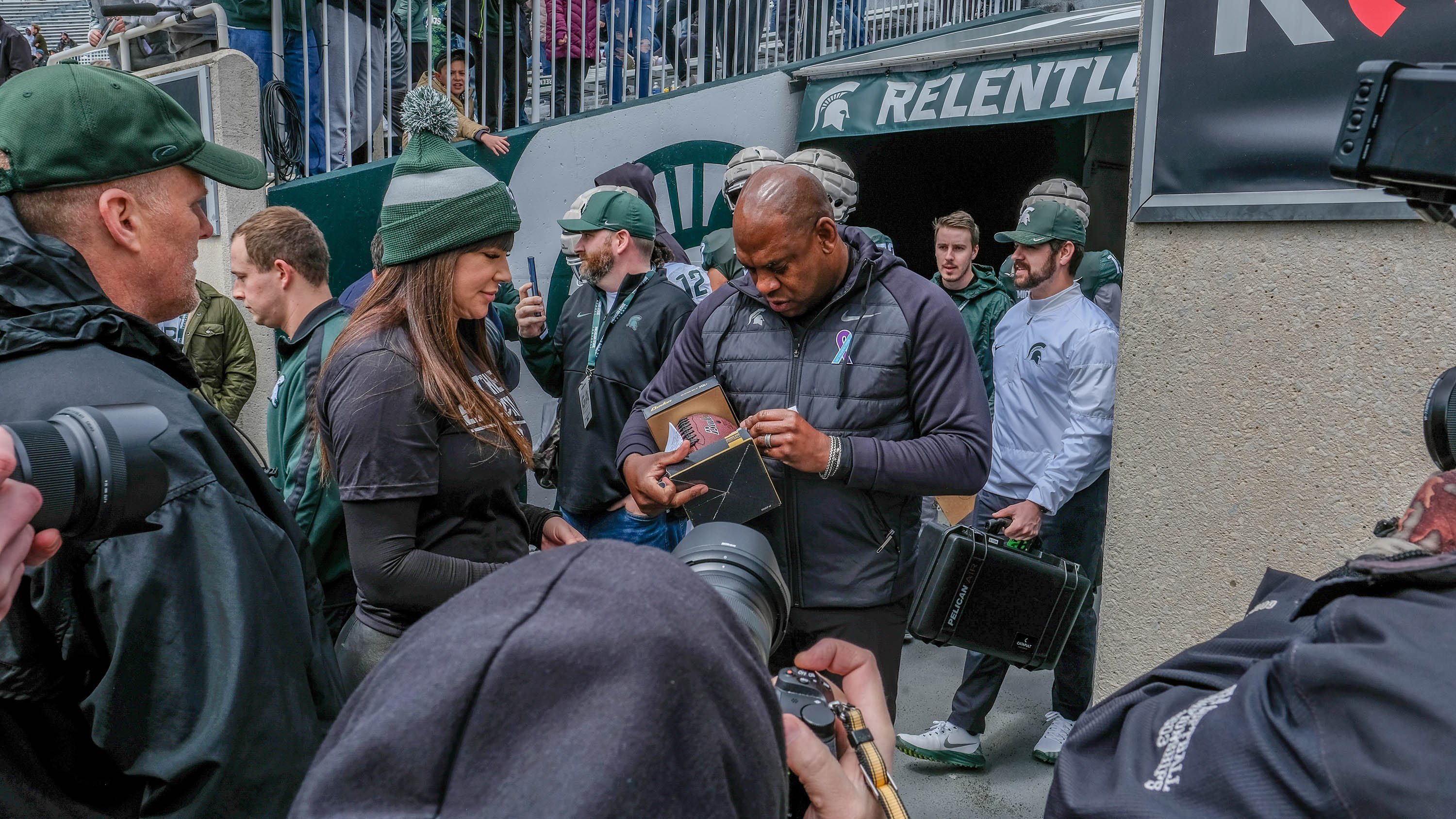 Mel Tucker with group of fans, signing football