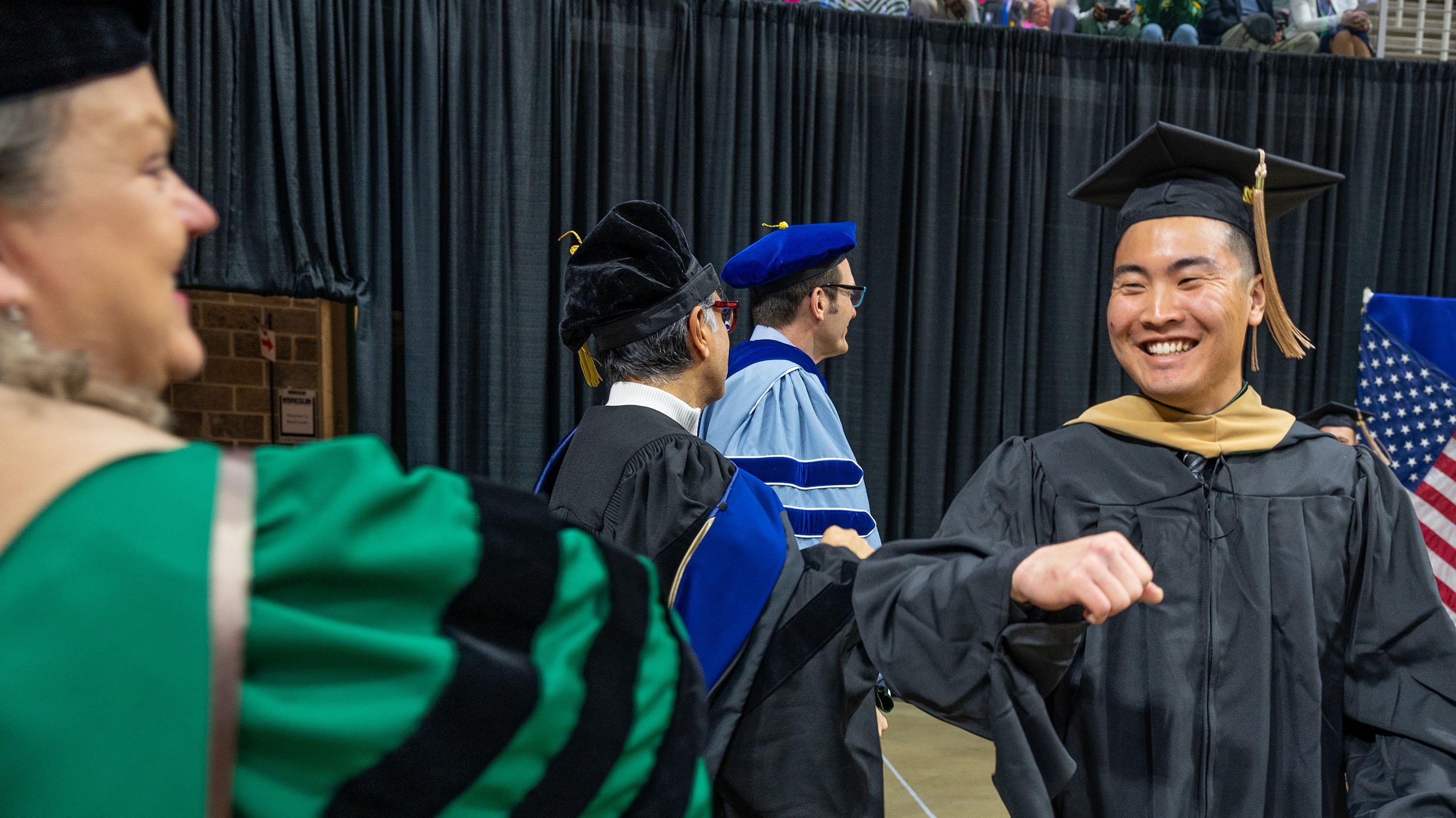 Professor Judith Whipple bumping elbows with MBA grad at commencement