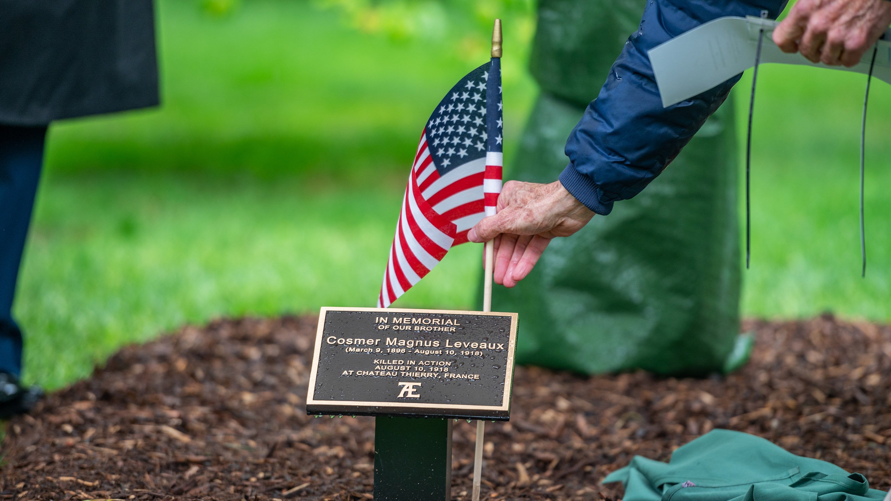 Hand placing small American flag behind new Cosmer Leveaux plaque