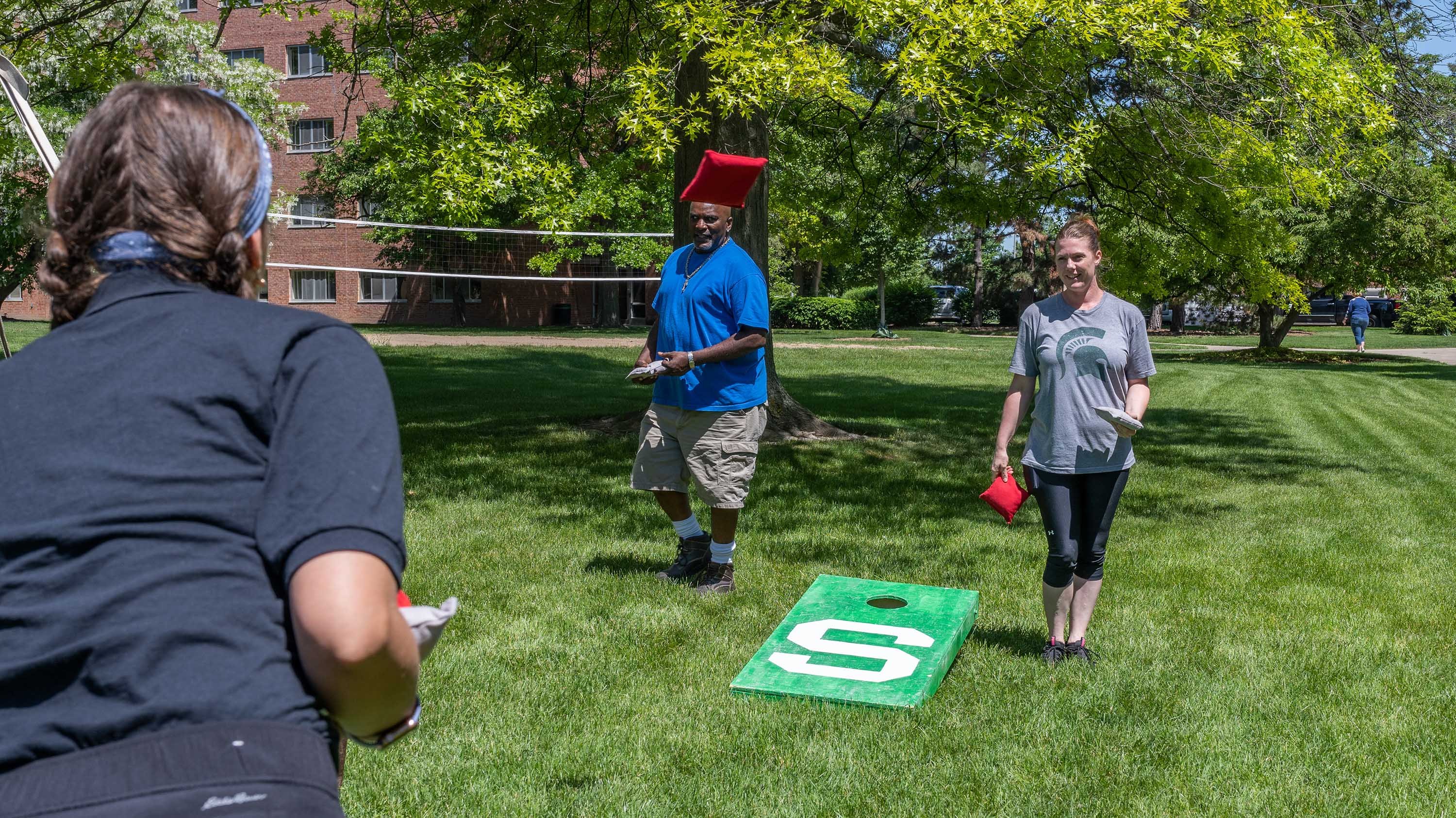 Three RLS/SLE employees playing cornhole