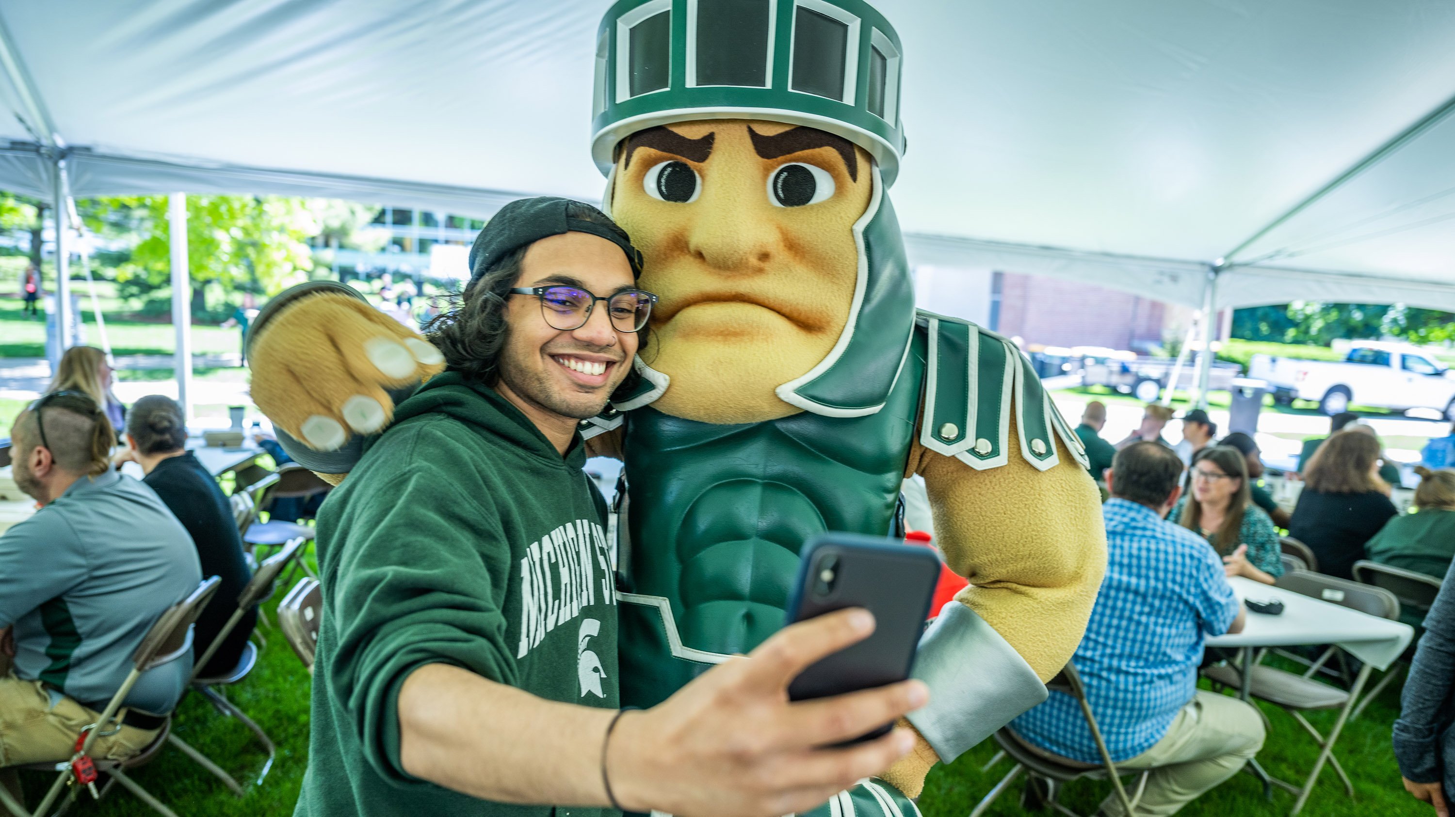 SLE employee taking selfie with Sparty mascot