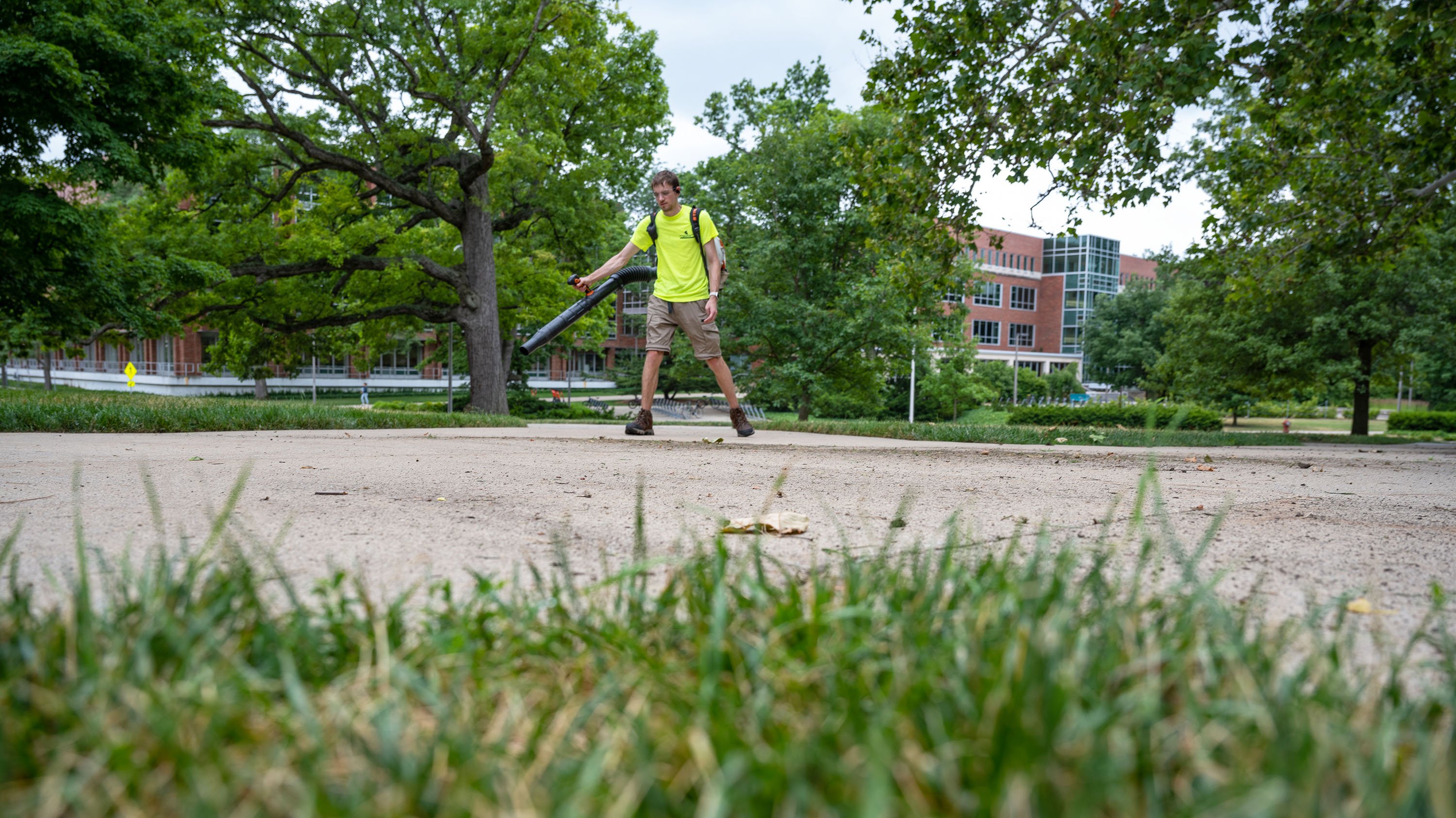 IPF crew member using leaf blower on sidewalk