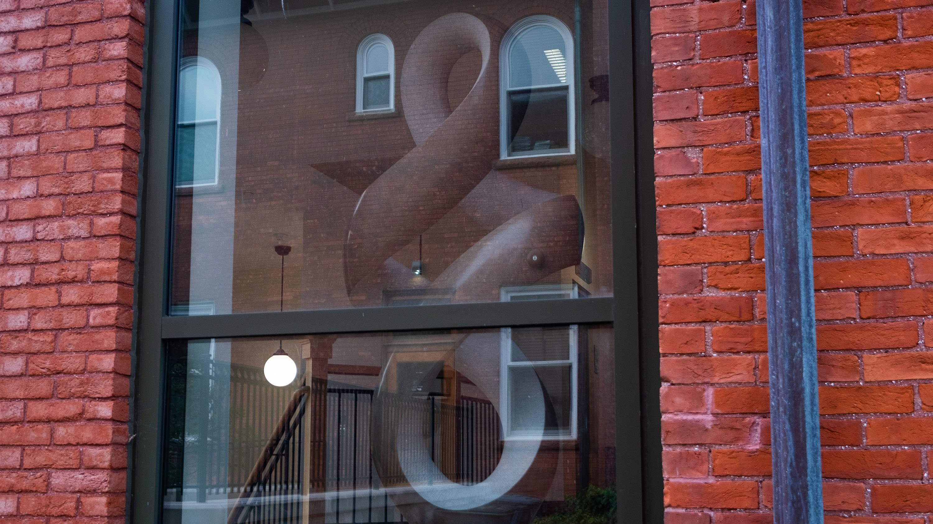 Aabiji Bidemigan Bimaadiziwin, a curved limestone sculpture, in the window of Cook-Seevers Hall