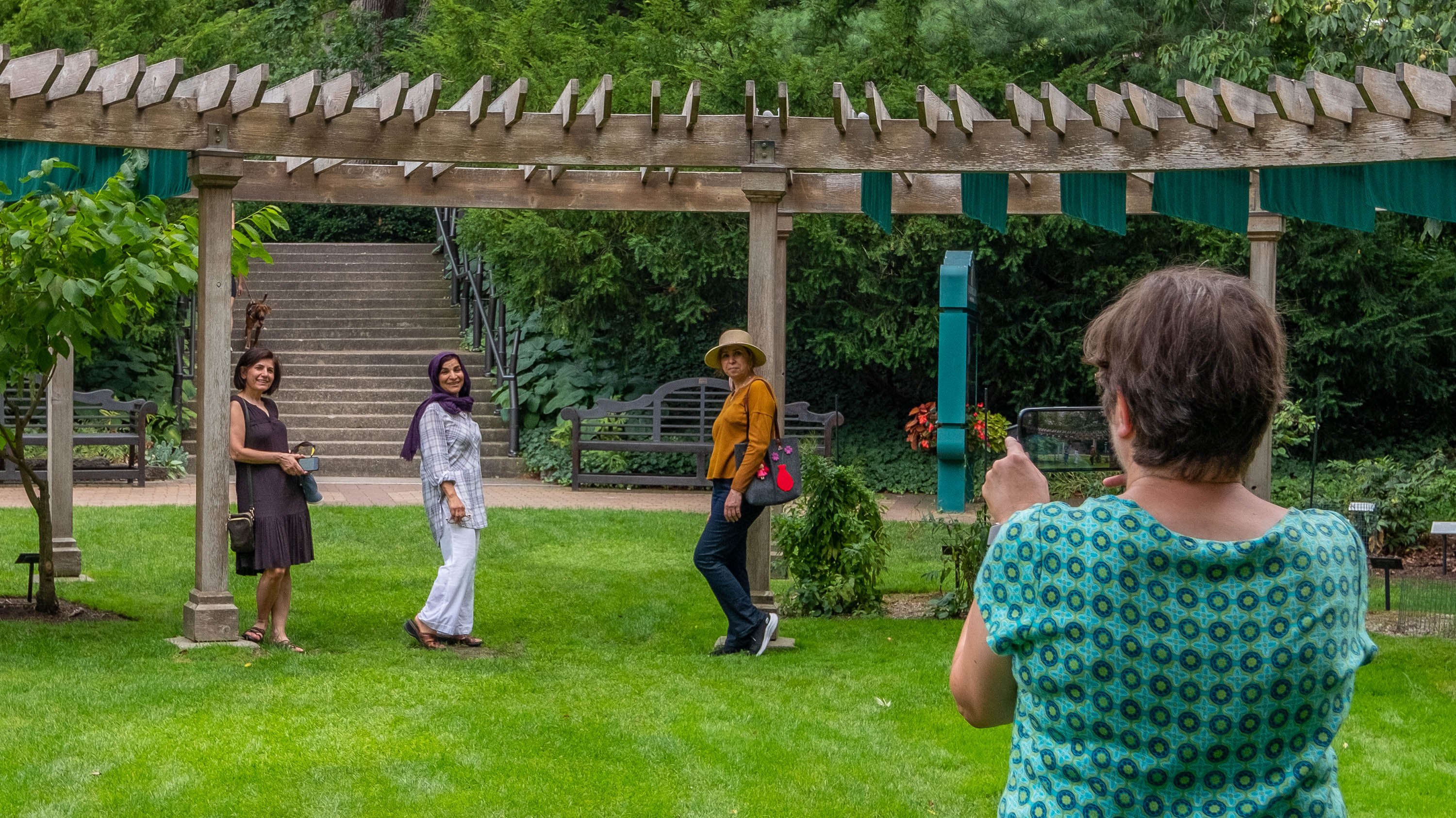 Woman taking picture of three people posing under pergola in Beal Botanical Garden