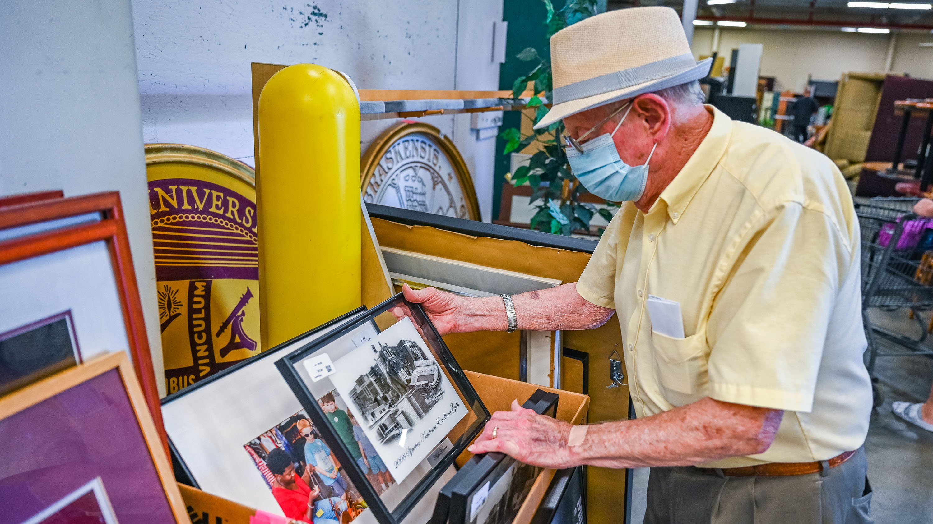 Person at the MSU Surplus Store looking through framed art