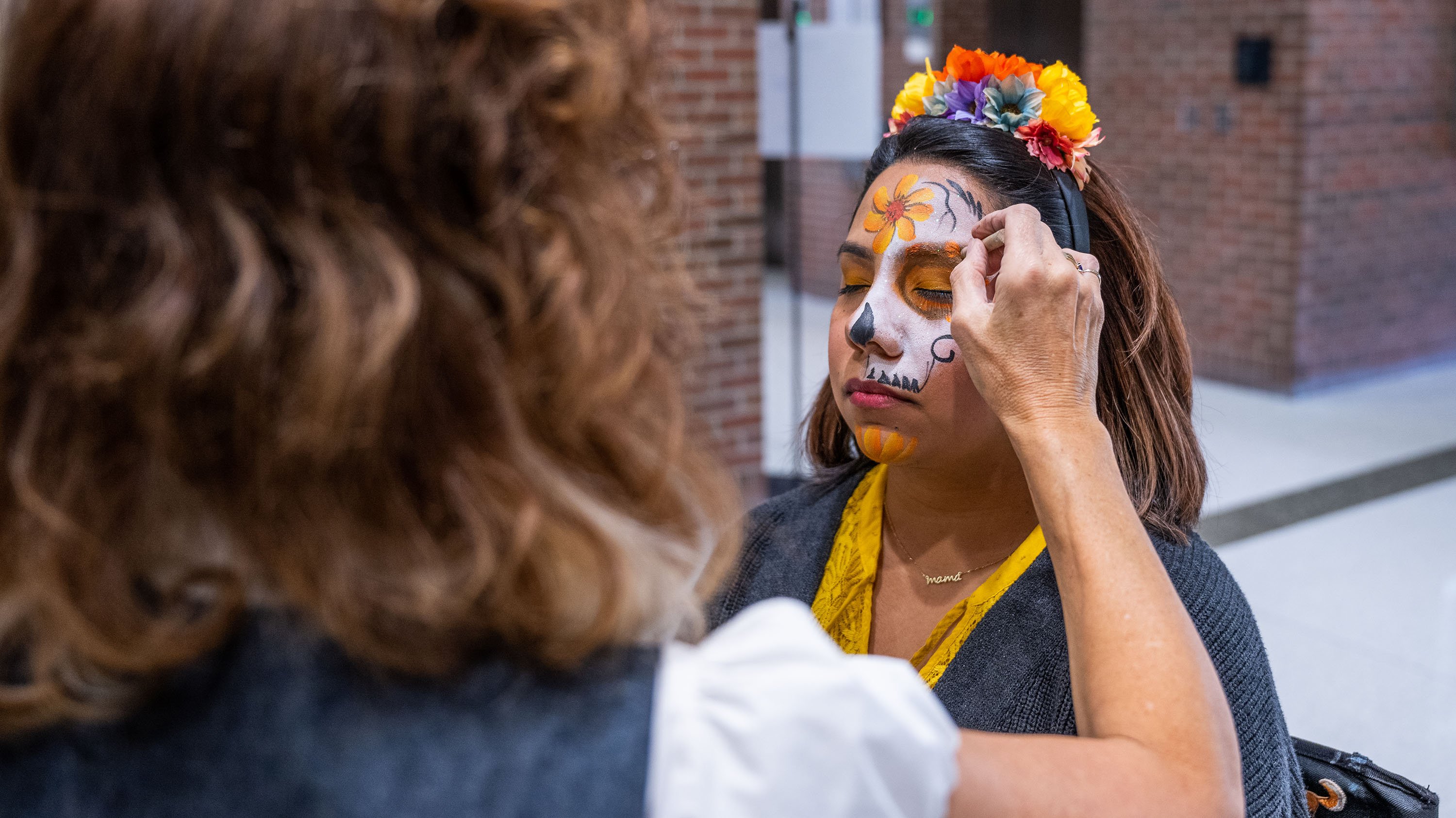 Person getting their face painted with a sugar skull design