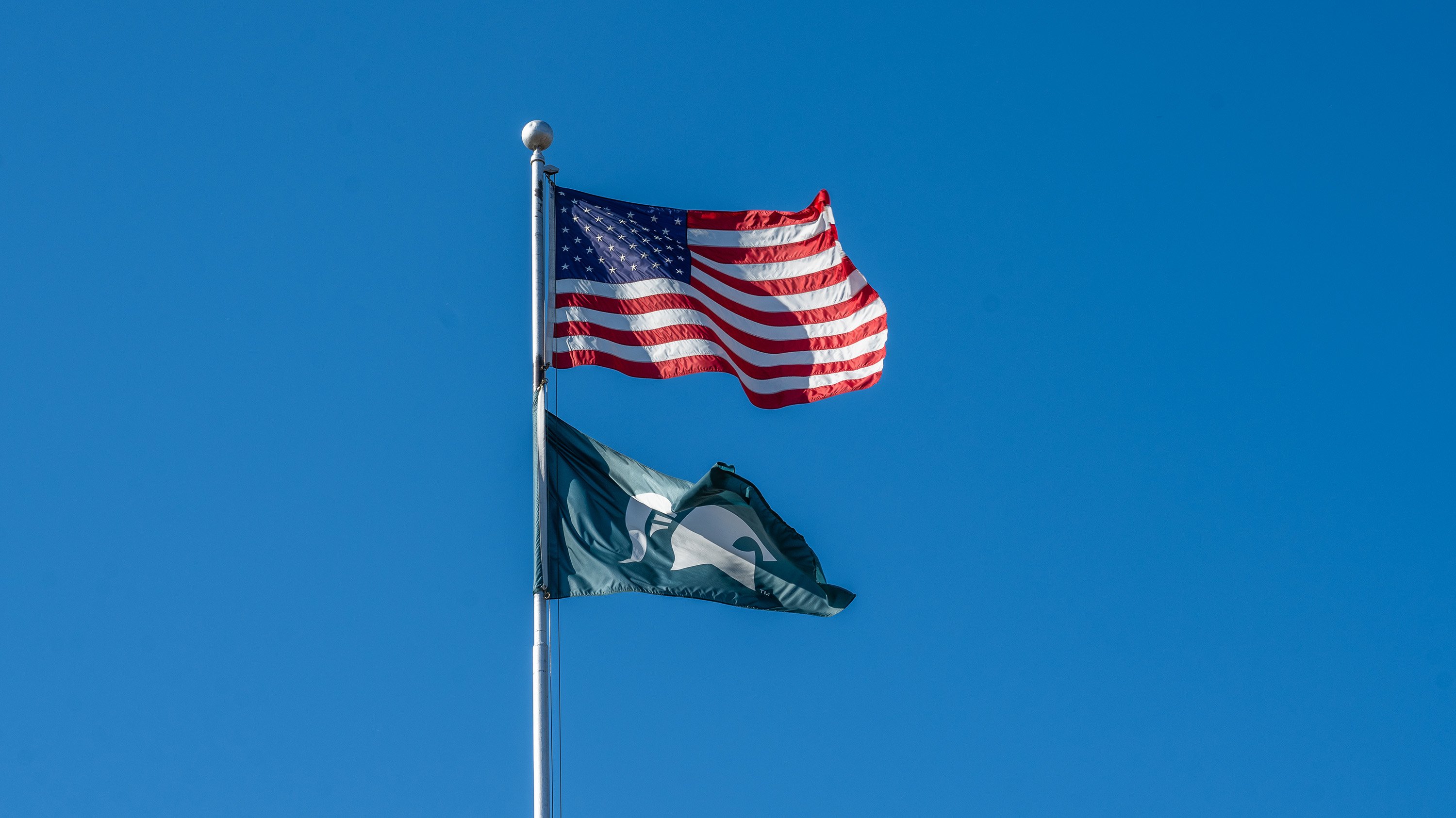 American flag flying above Spartan flag