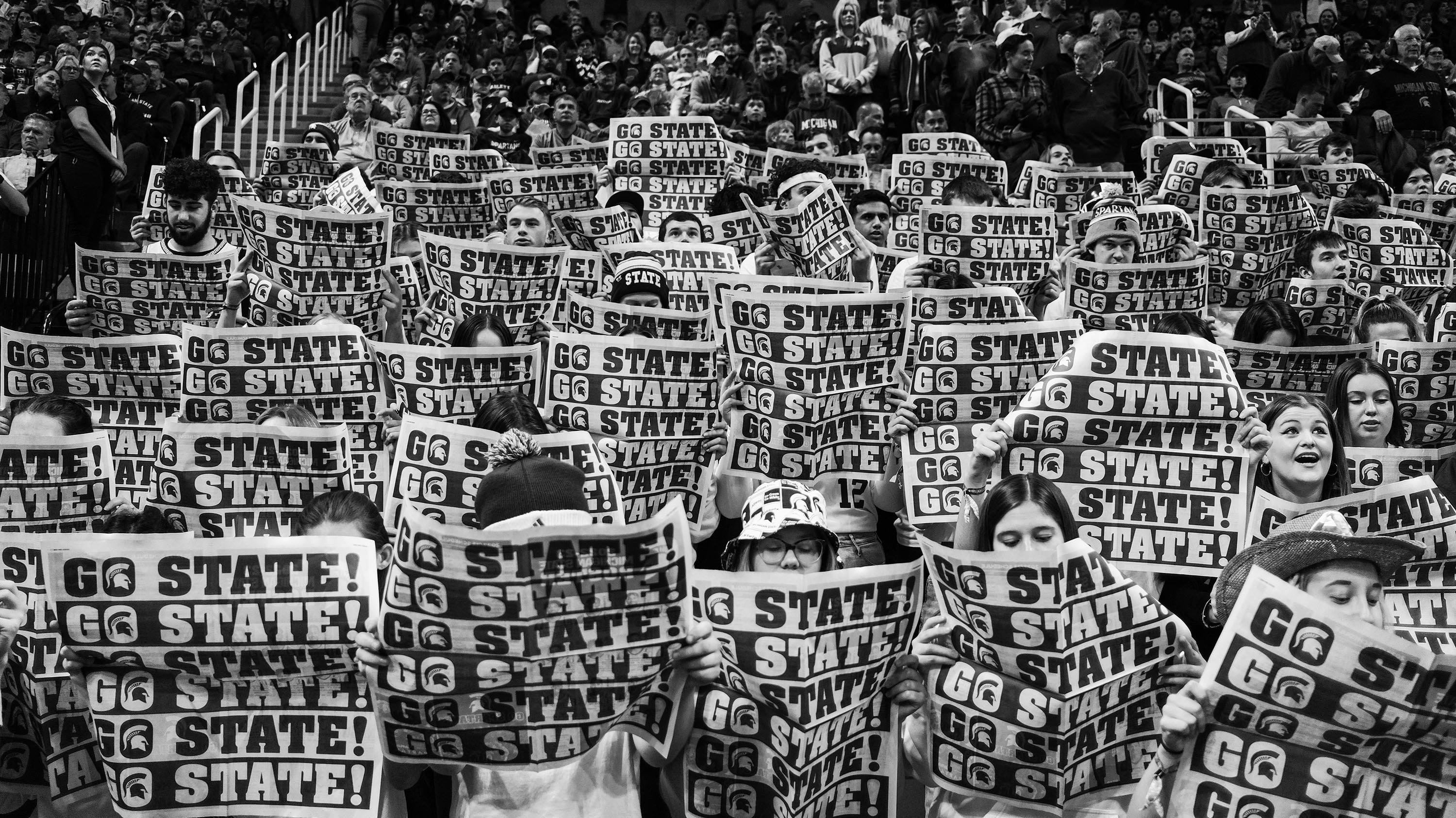 Black and white image of Izzone holding up newspapers