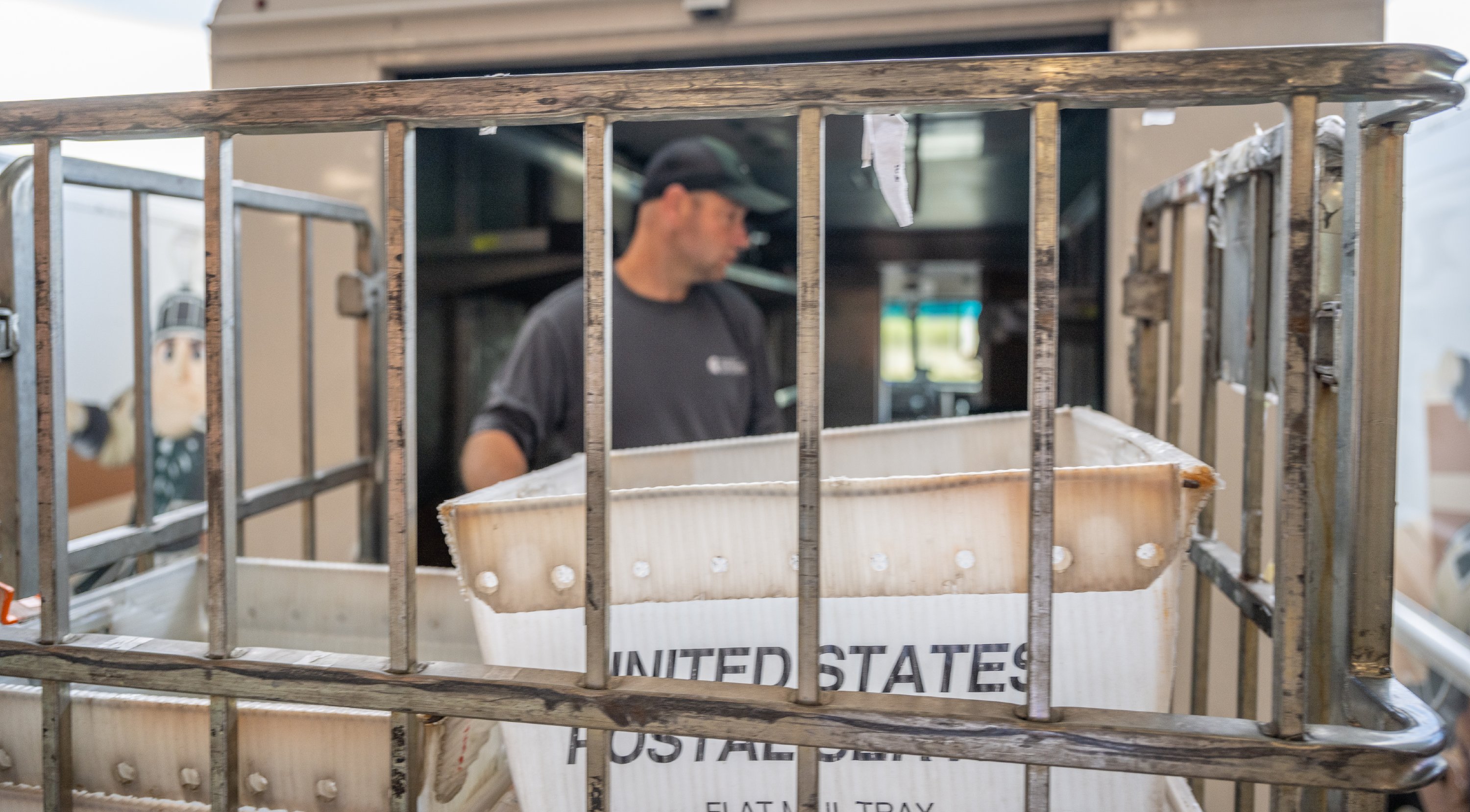 A man works behind a rack loaded with United States Postal Services boxes.