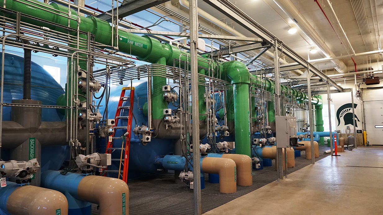 Blue, green and tan tanks and pipes fill the left side of a room.