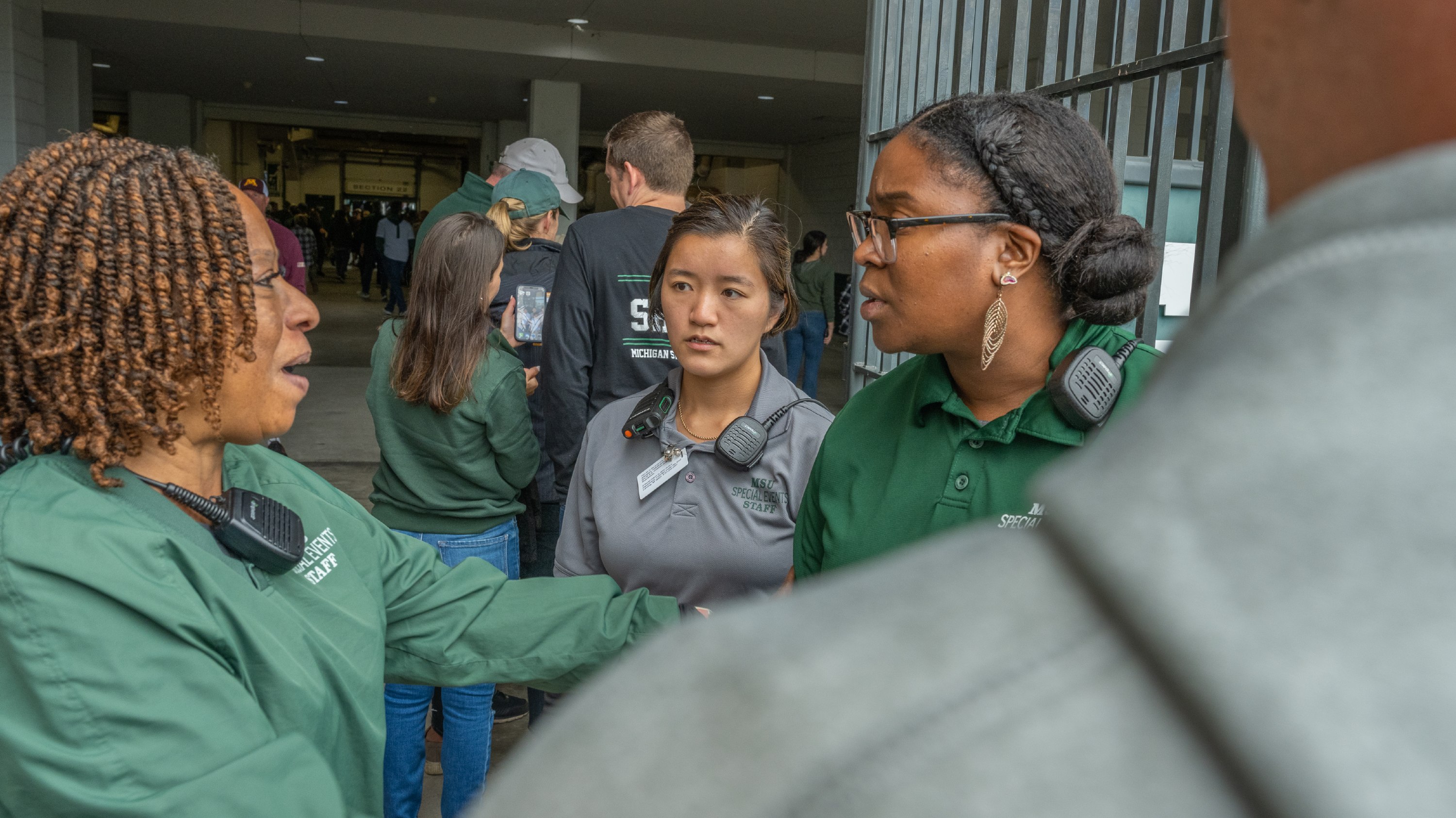 Annie Kovach speaks with fellow greencoats at a Spartan Stadium entrance.