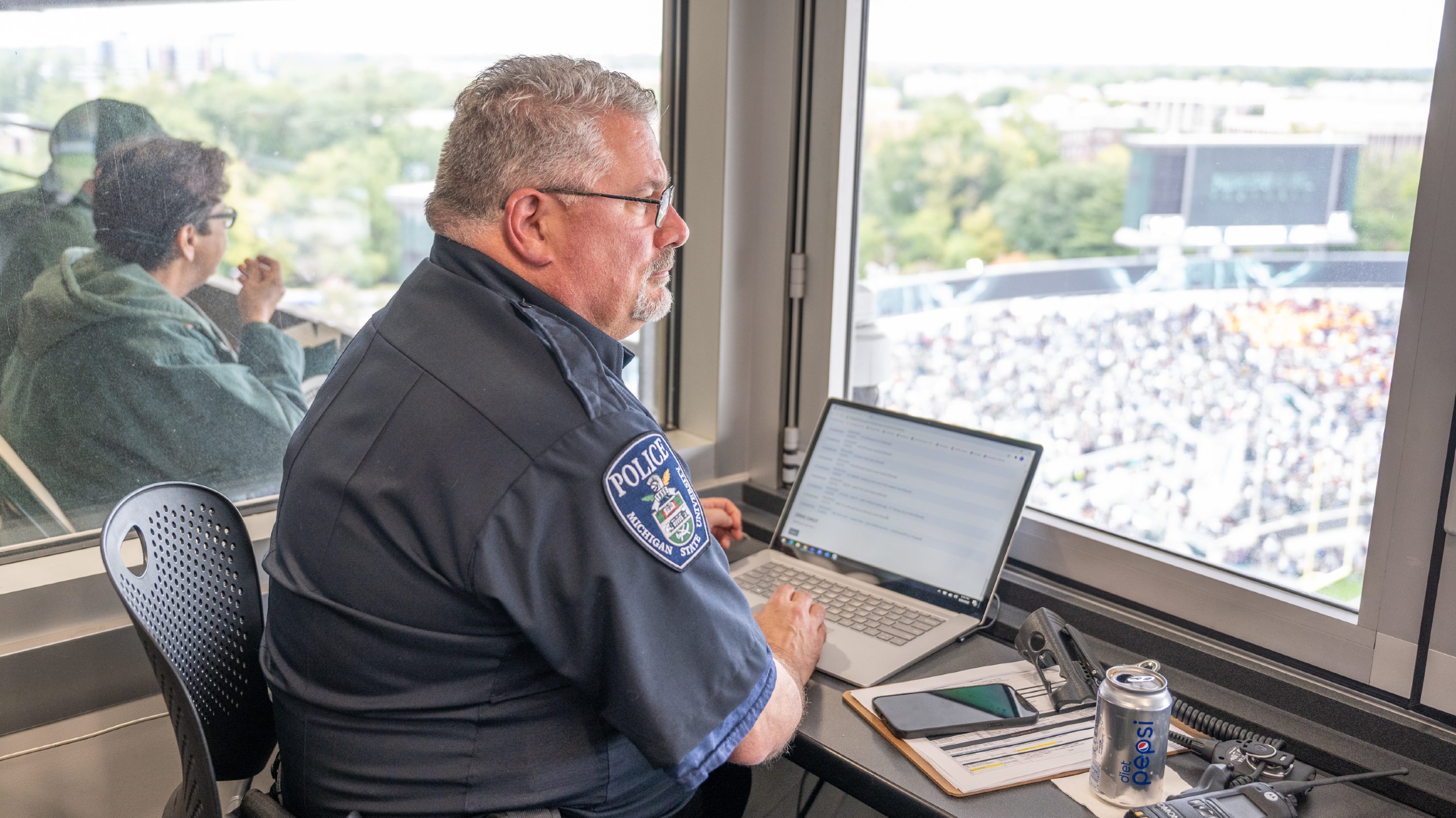 Doug Monette sits in front of a computer at the police command post inside of Spartan Stadium.