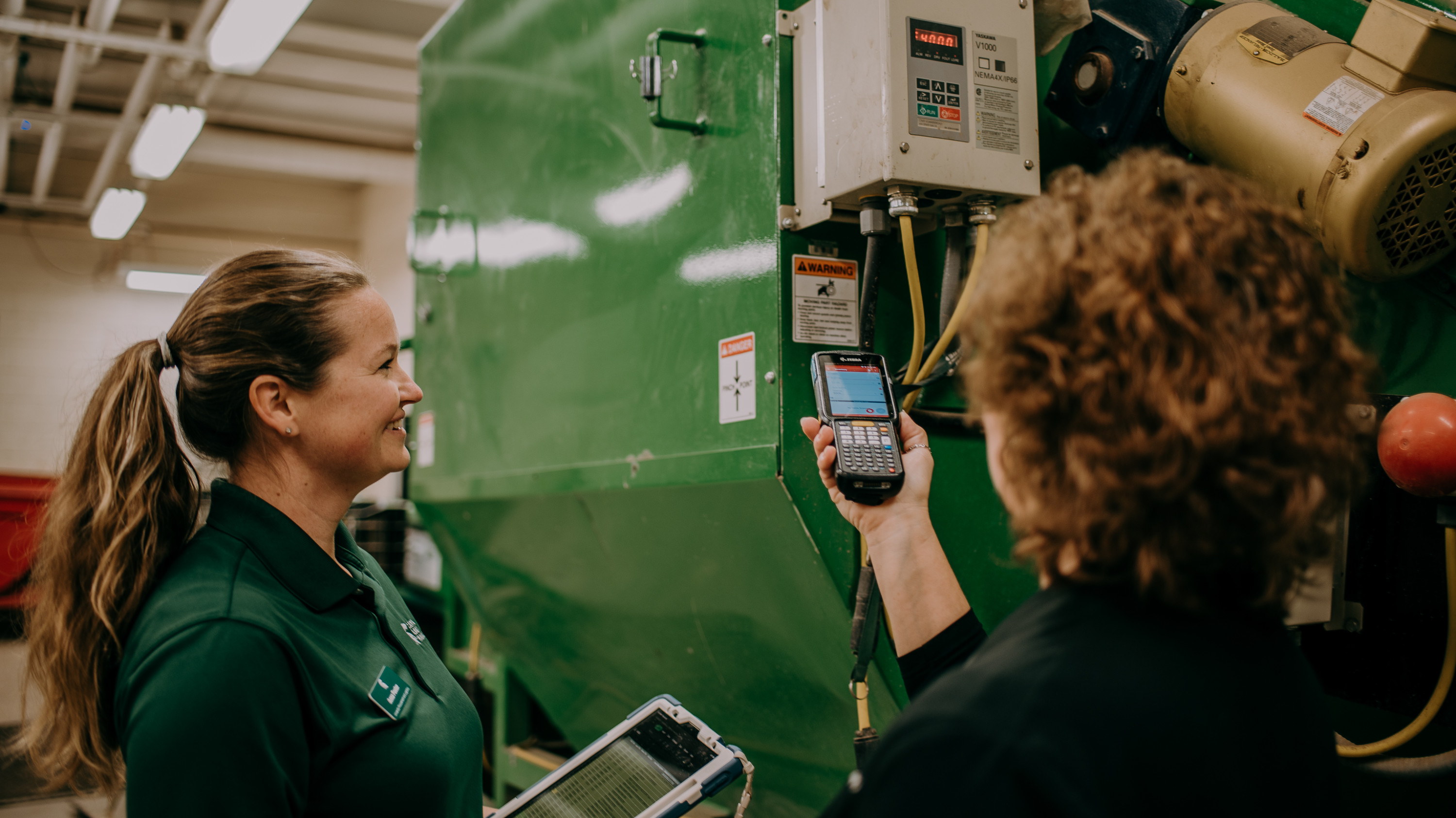 Anna Foster looks on as Debbie Smith scans a large green metal potato dryer.