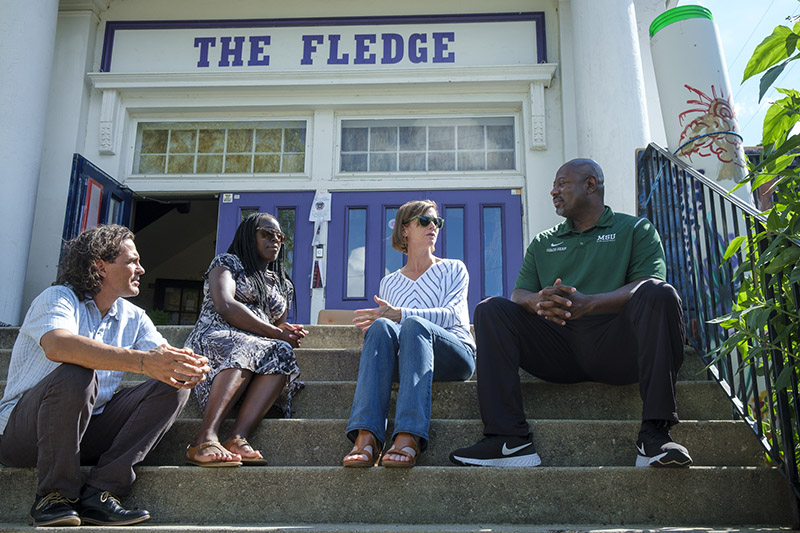 Carole Gibbs (Criminal Justice), speaks with fellow researchers Jennifer Cobbina (Criminal Justice), and Sean Hankins (Psychology) at The Fledge Community Center in Lansing. Jerry Norris, far left, runs The Fledge and is helping to facilitate their project titled