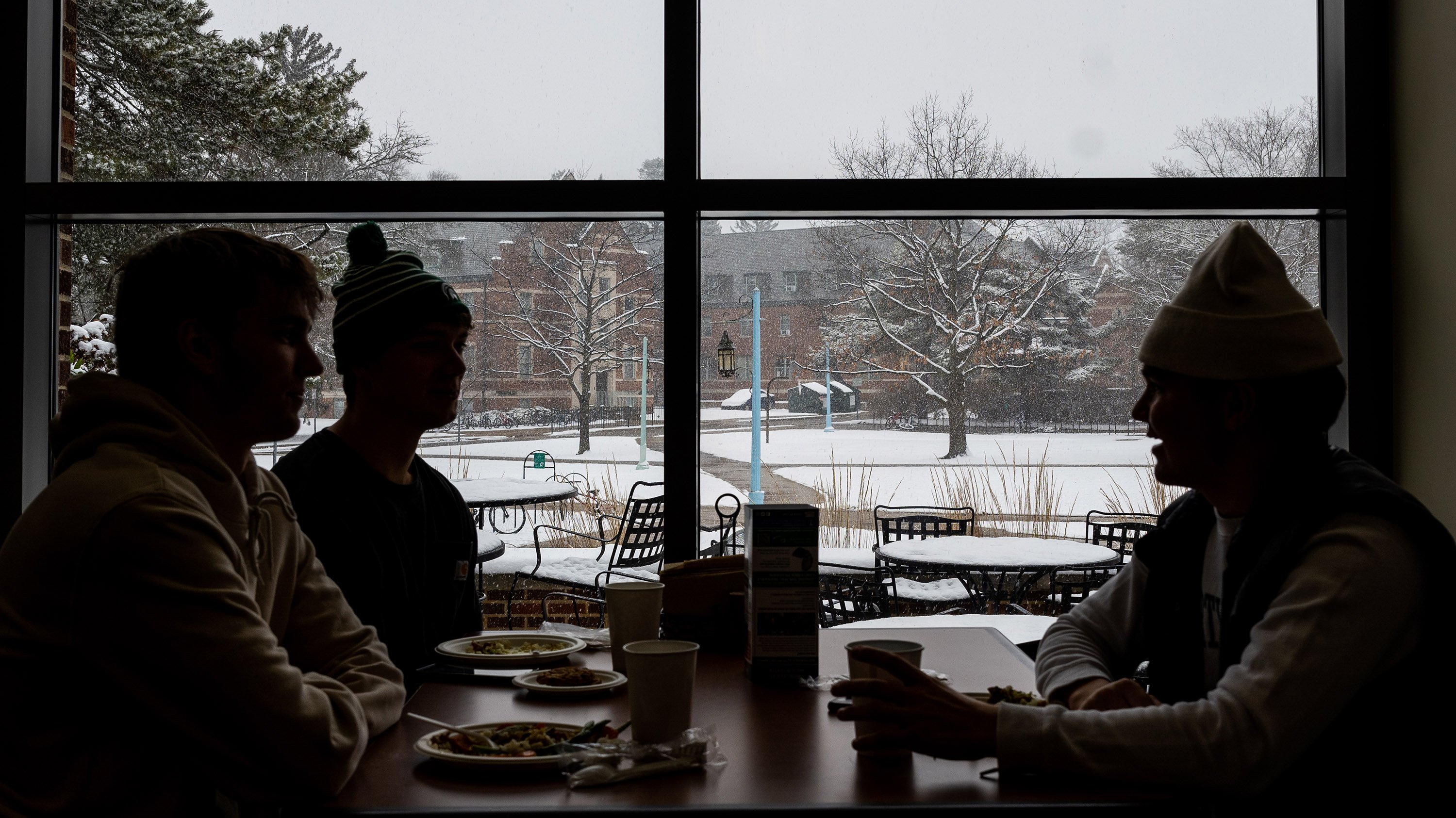 Silhouetted students eating in dining hall