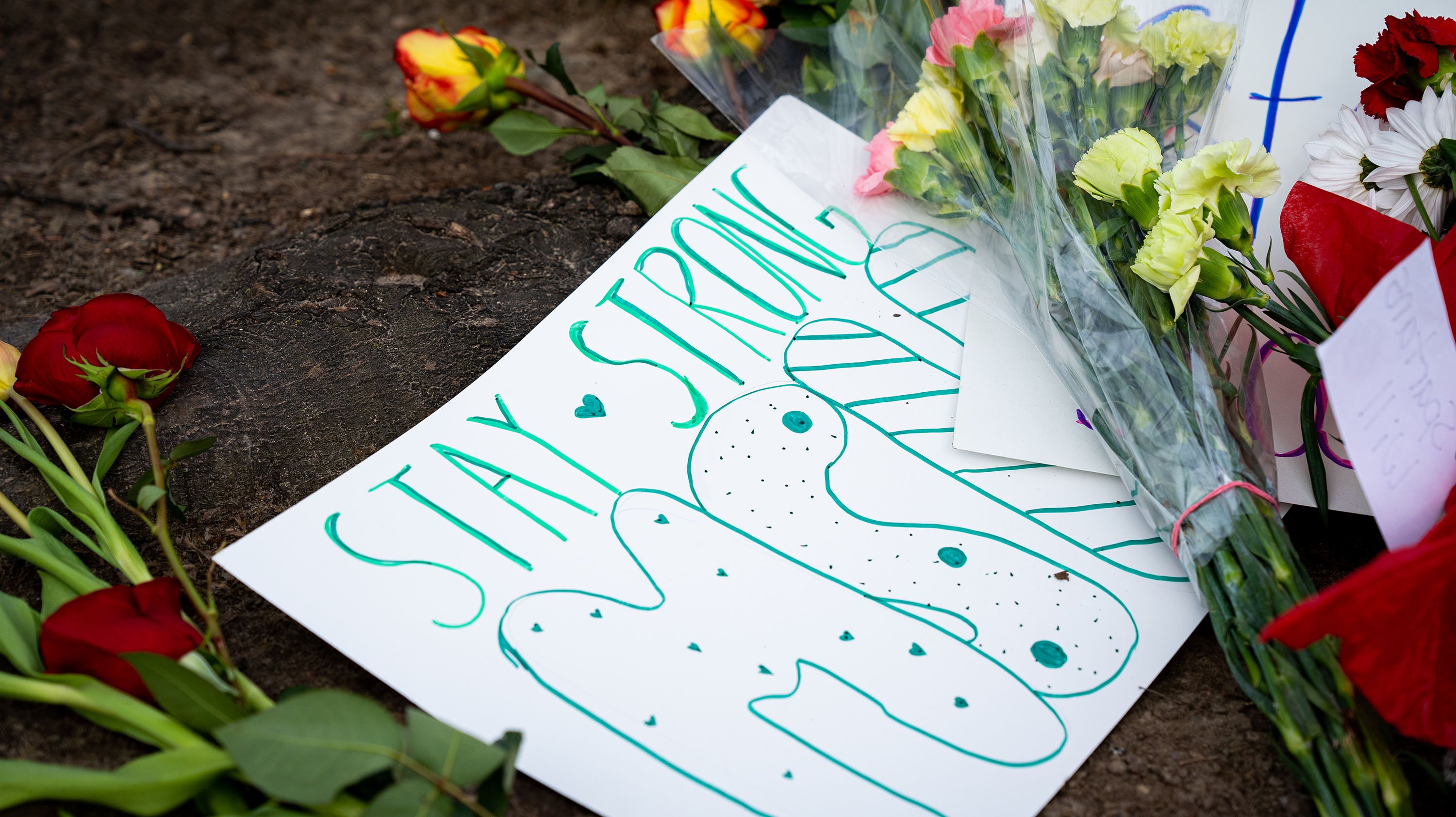 Flowers surround a message on paper that says Stay Strong MSU