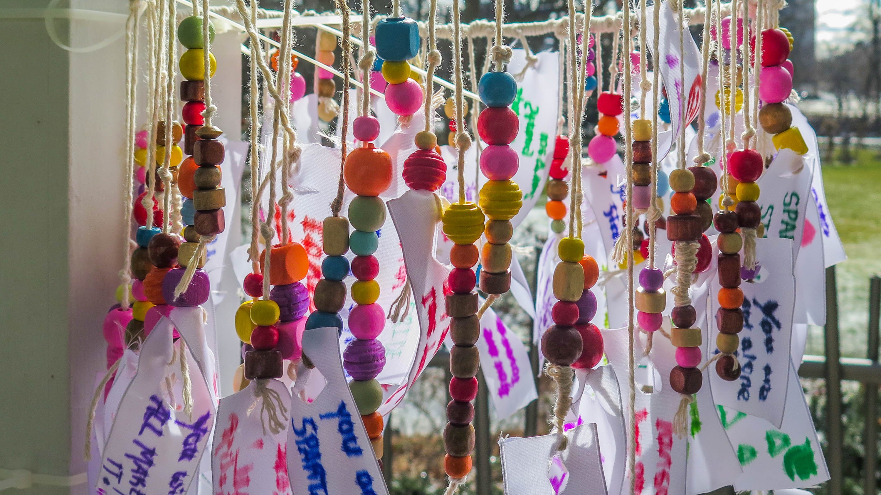 Beal staff hang a colorful mobile of fabric strips and beads