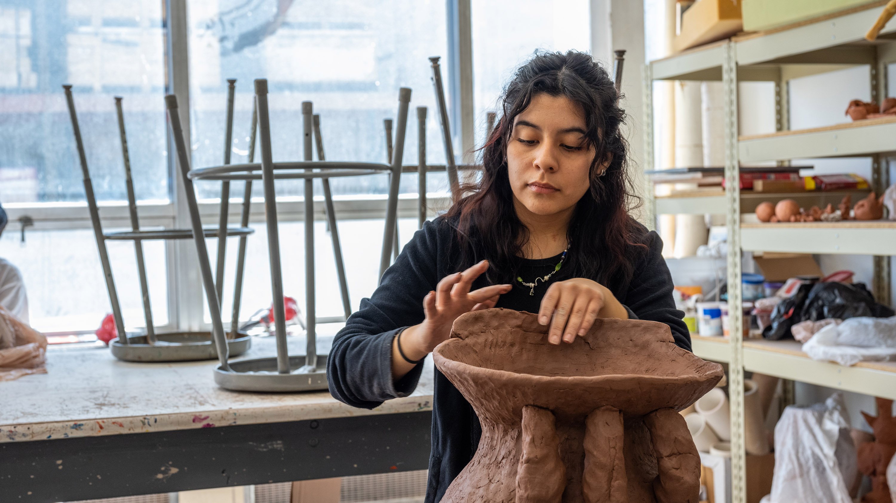 Student building large vessel out of clay