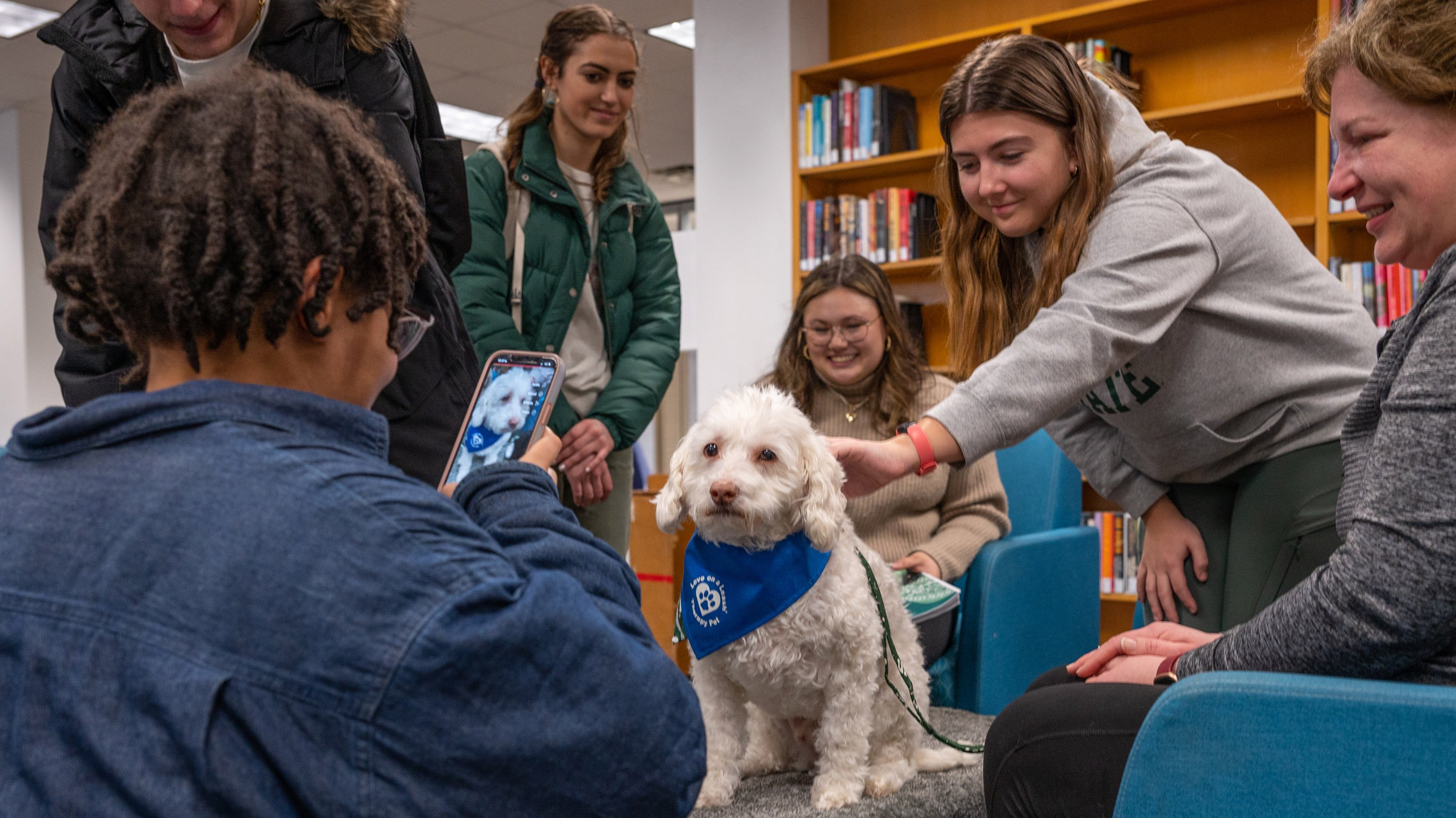 Students petting and taking picture of therapy dog