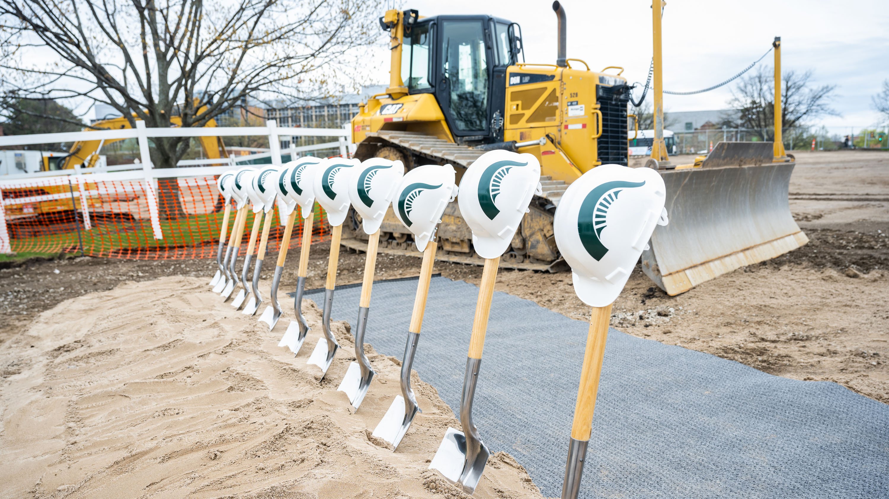 Shovels and hard hats in ground prepared for groundbreaking ceremony