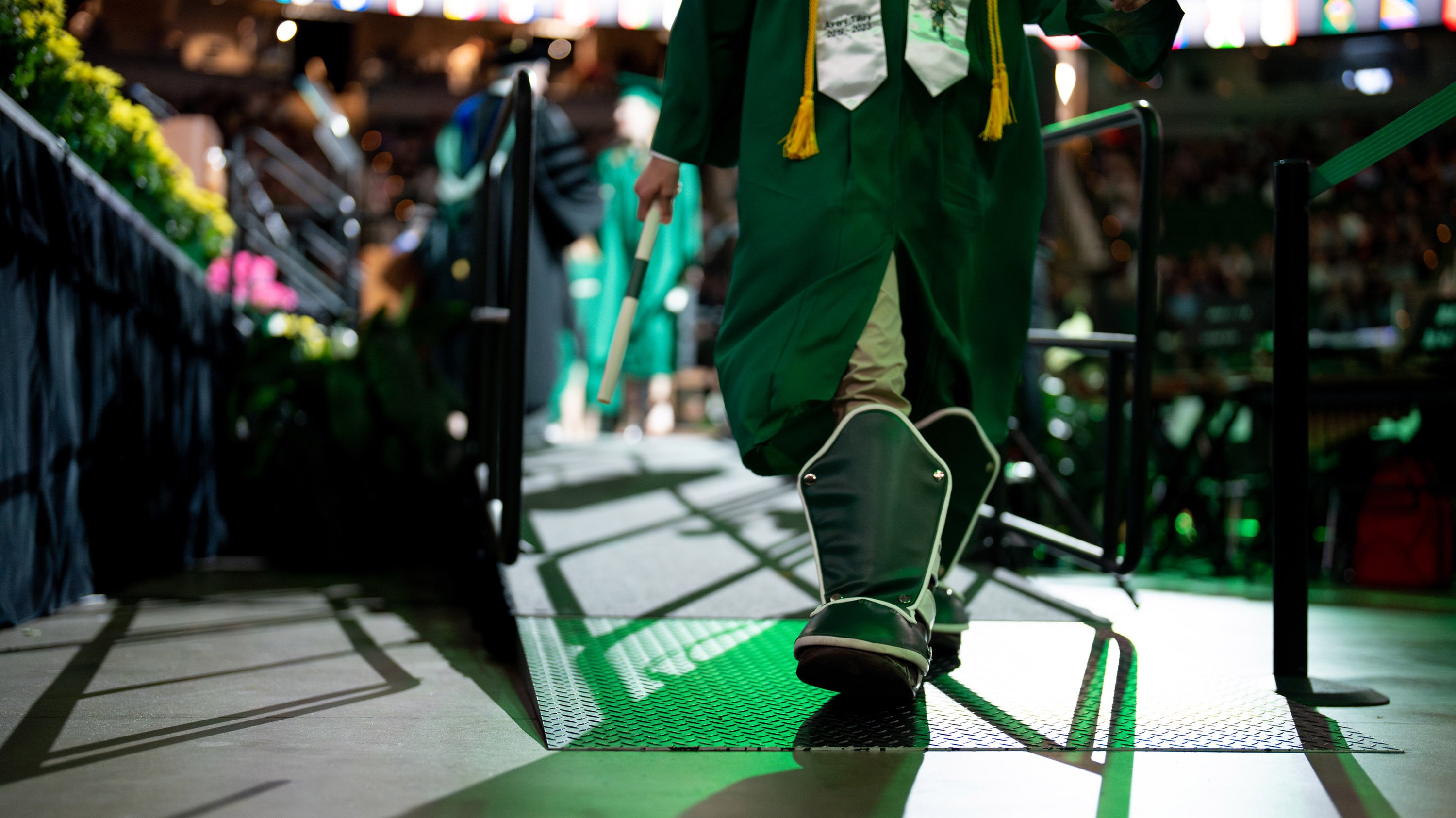 Graduate wearing Spartan mascot boots walking across the stage