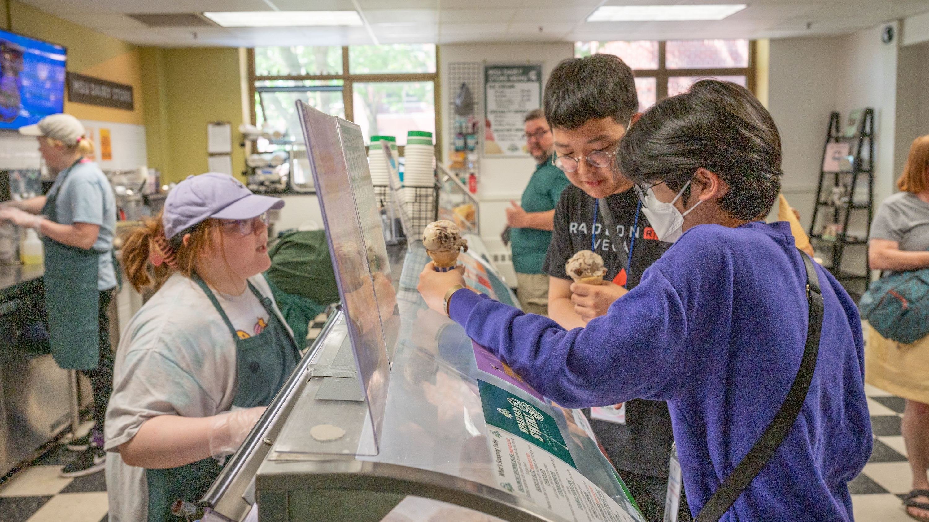 Customers hold ice cream cones at the MSU Dairy Store