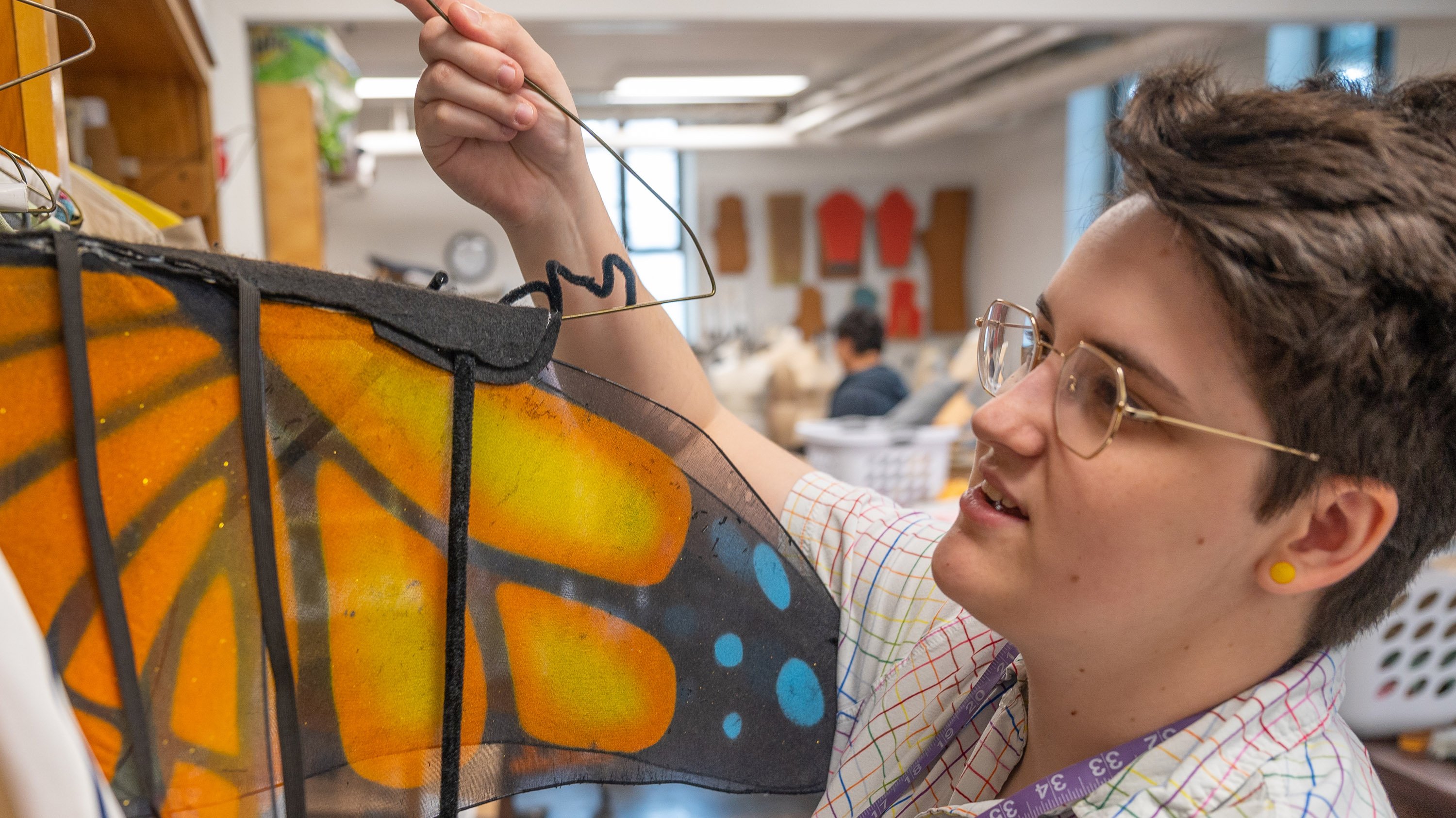 A student holding up a pair of butterfly wings in the MSU costume shop
