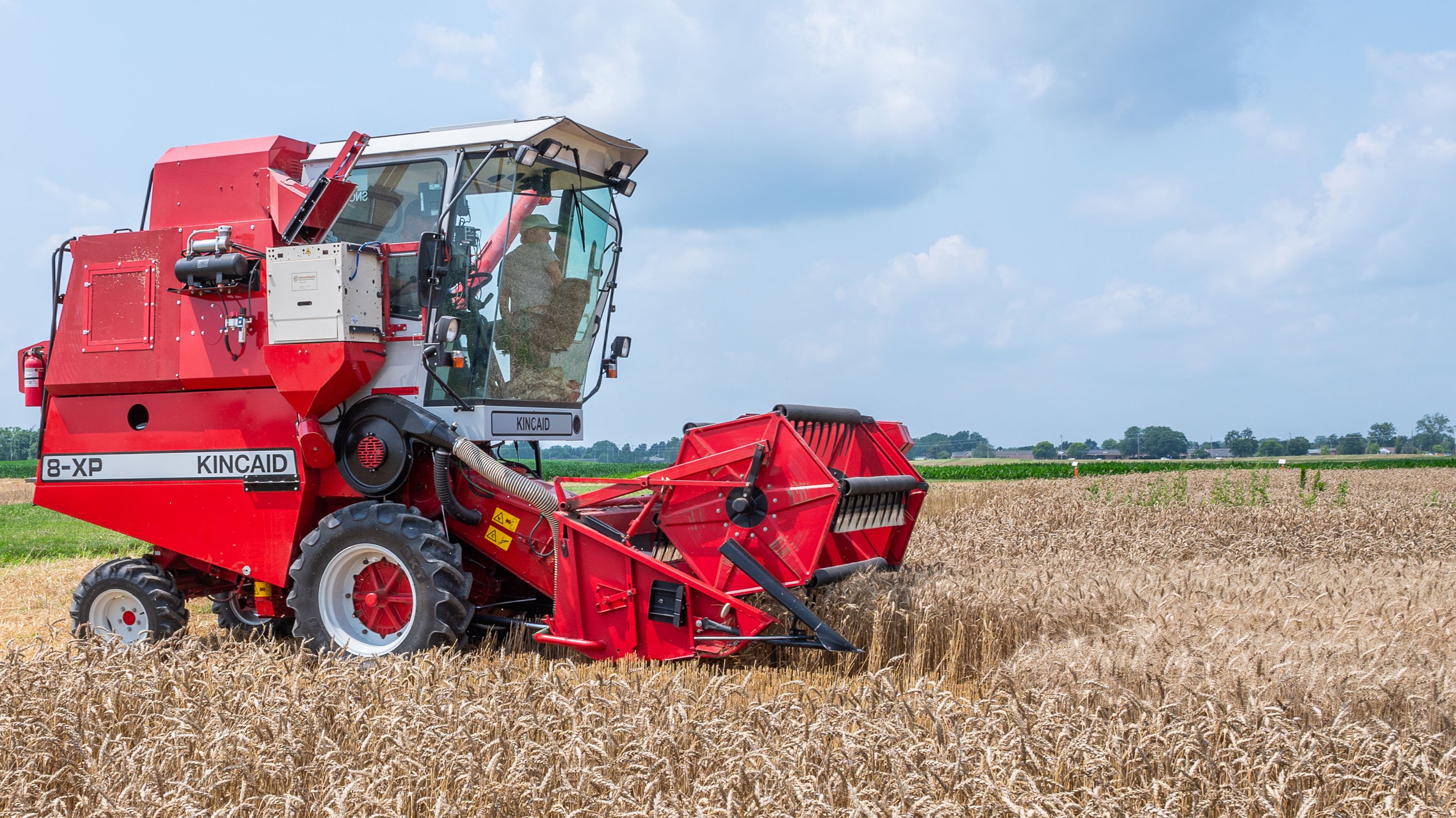 Red farm machine harvesting wheat