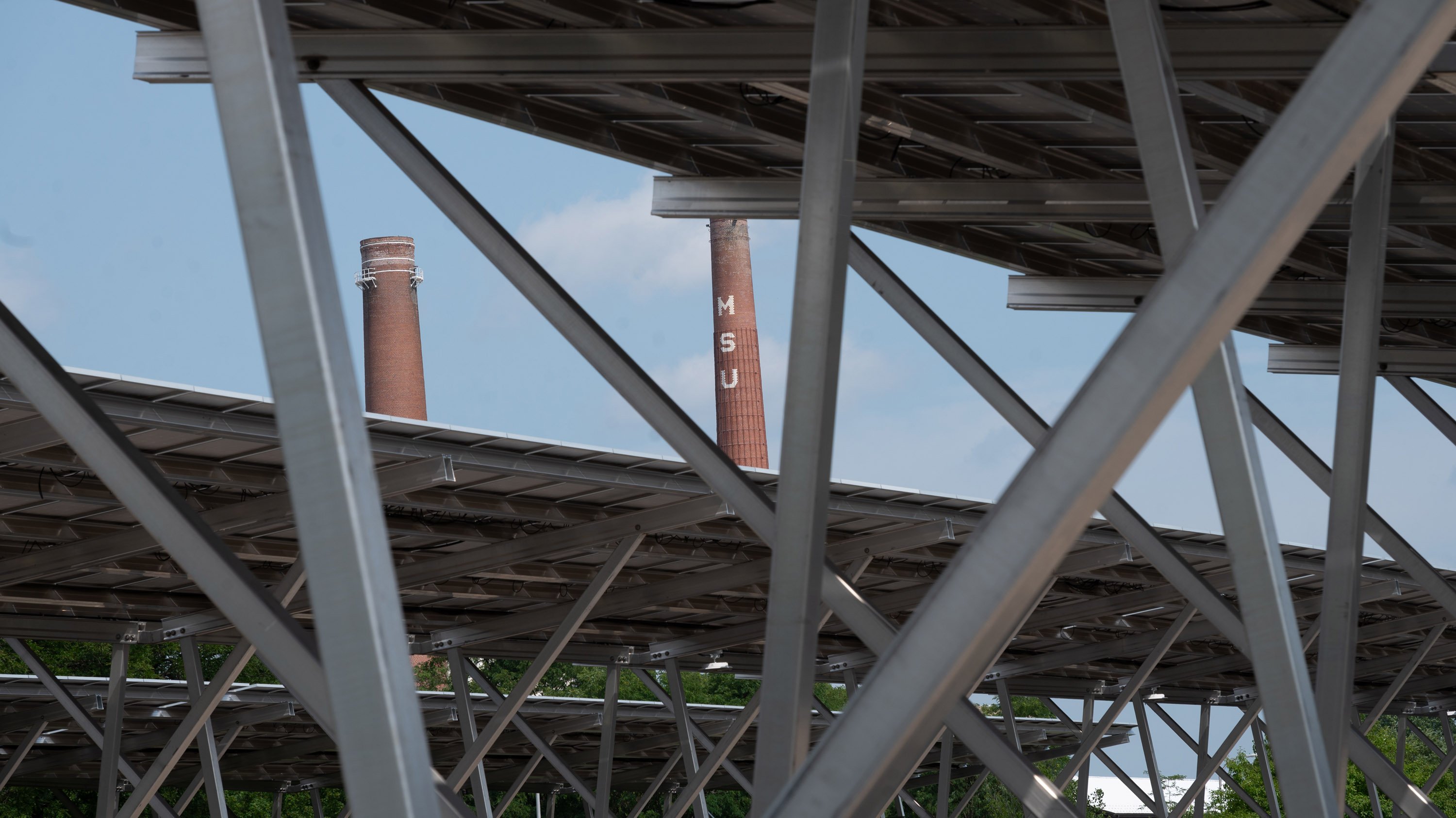 MSU smokestacks seen through gaps in solar carport