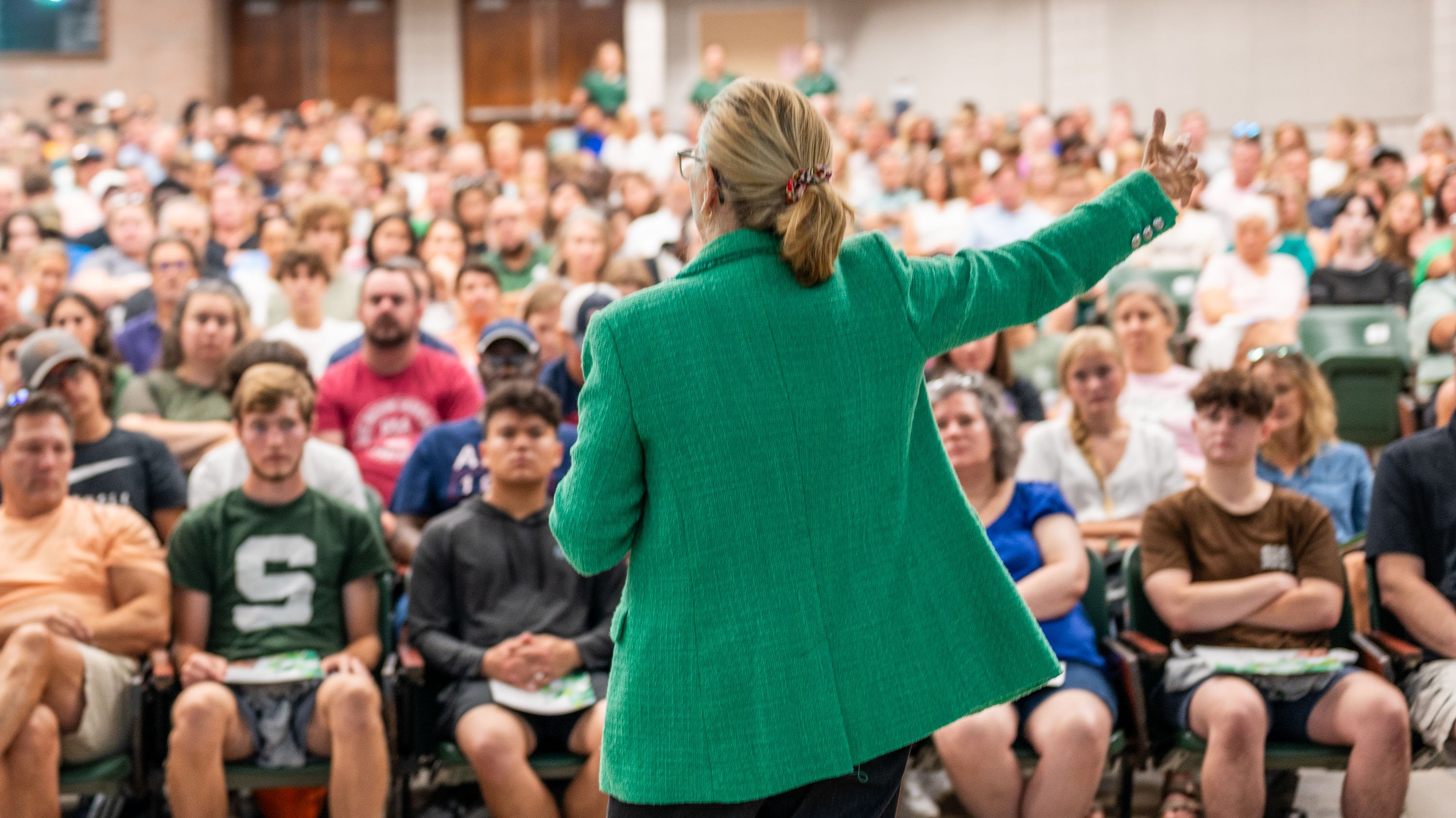 Teresa Woodruff stands in front of Green and White Day attendees