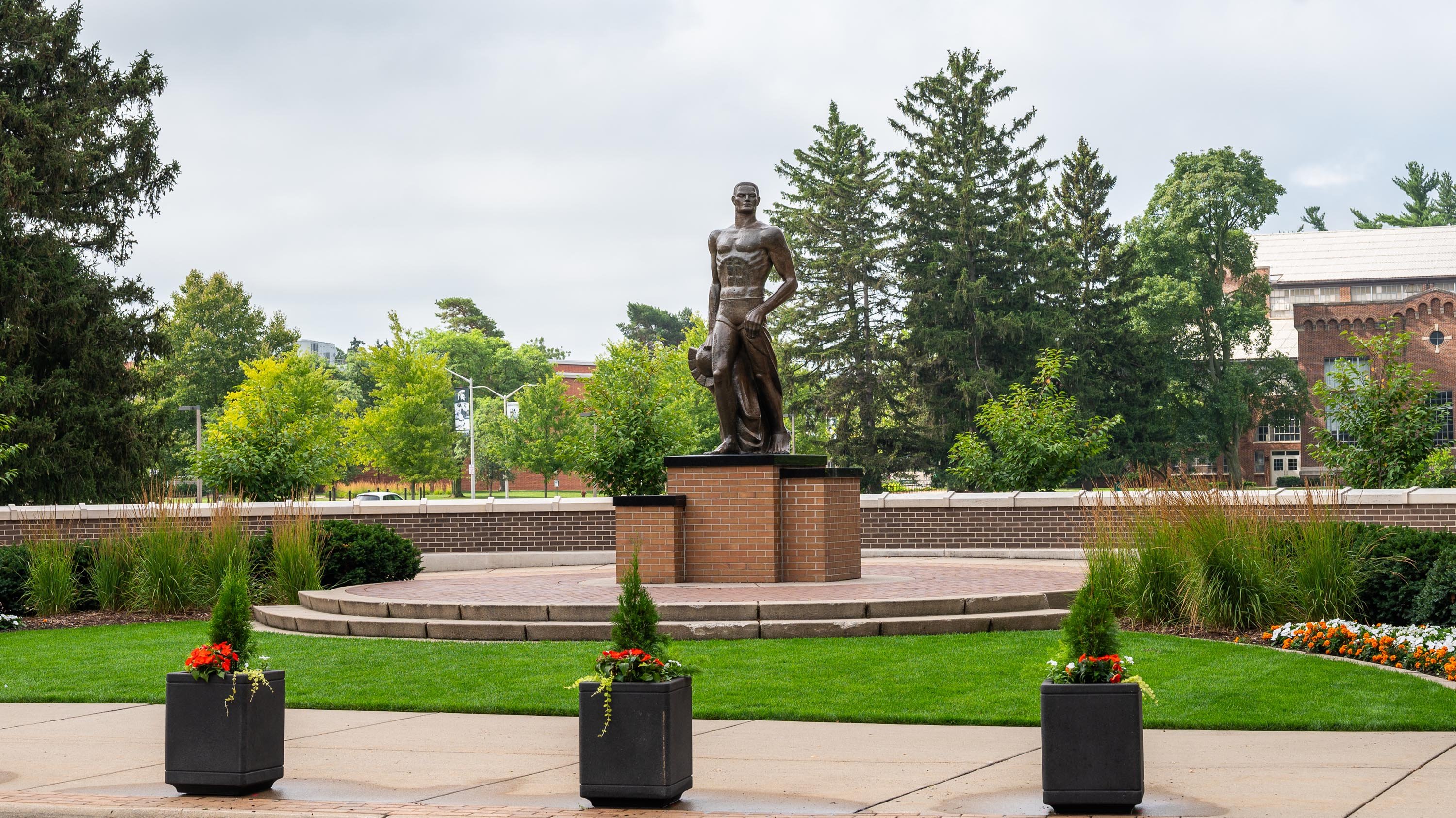 Planter boxes filled with flowers in front of the Spartan Statue