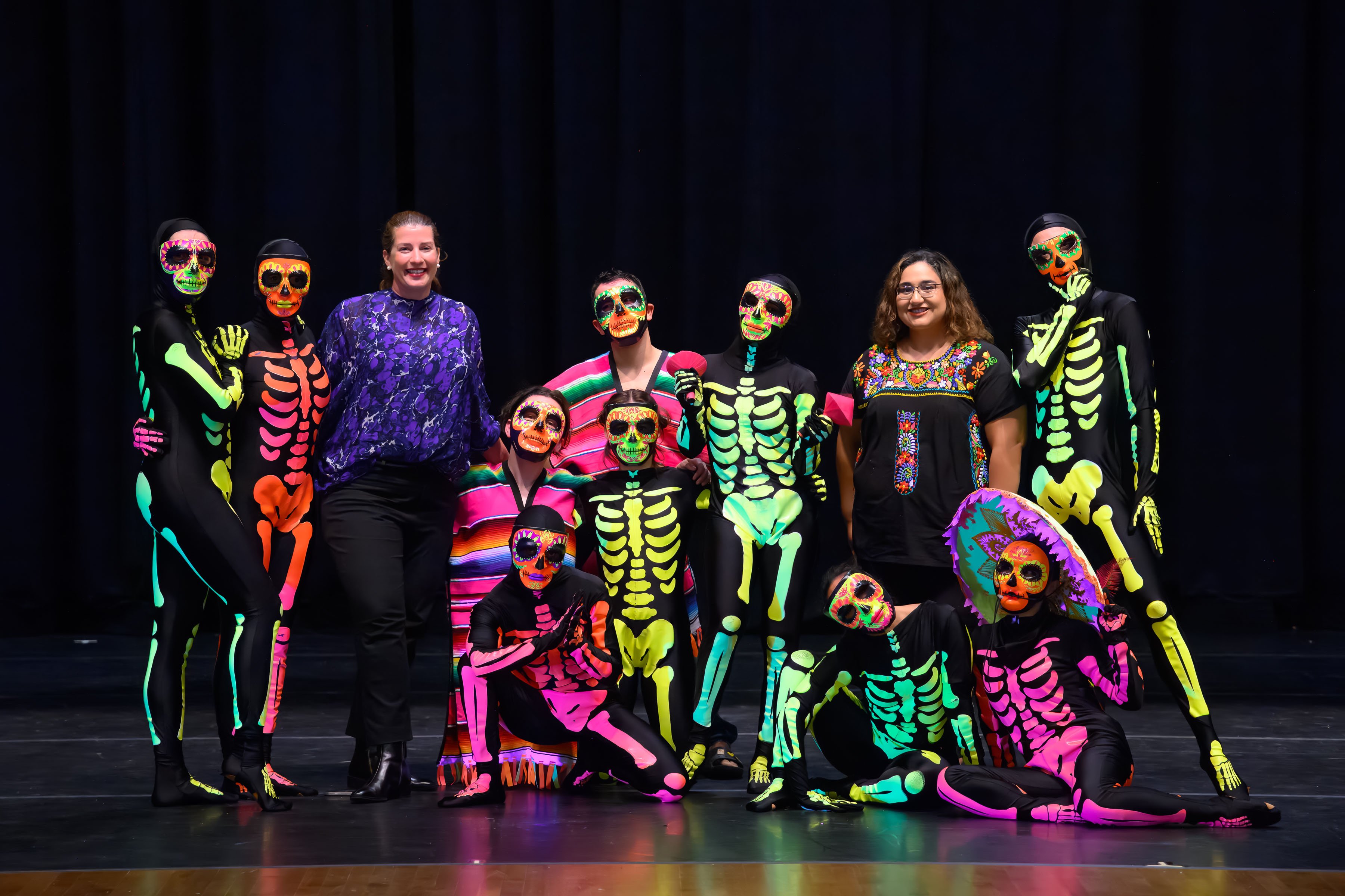 Ballet Nepantla dancers wearing colorful skeleton costumes, posing for a photo with Isabel Ayala and Isabel Montemayor-Vazquez