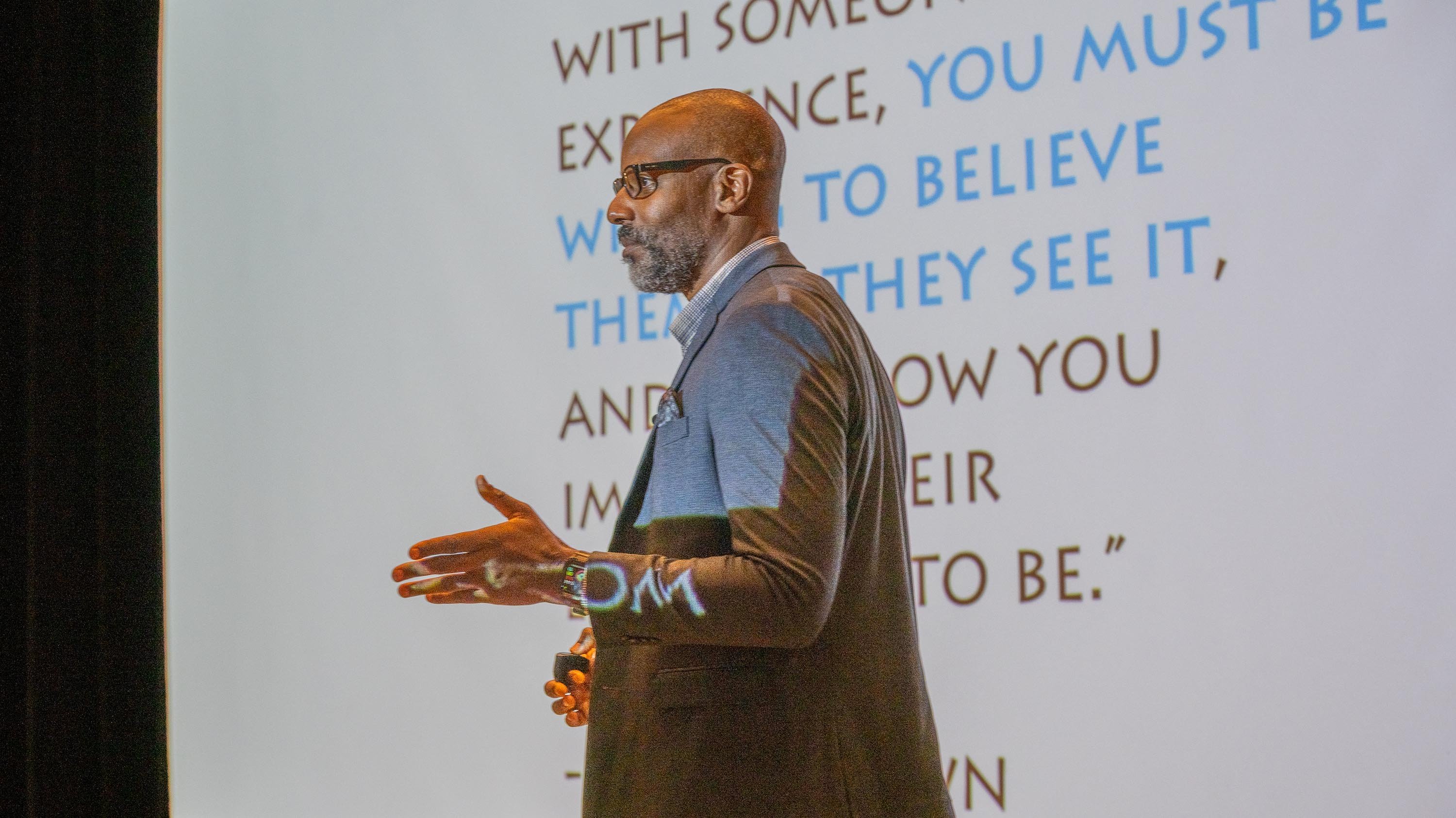 Doyin Richards giving presentation in front of projector screen