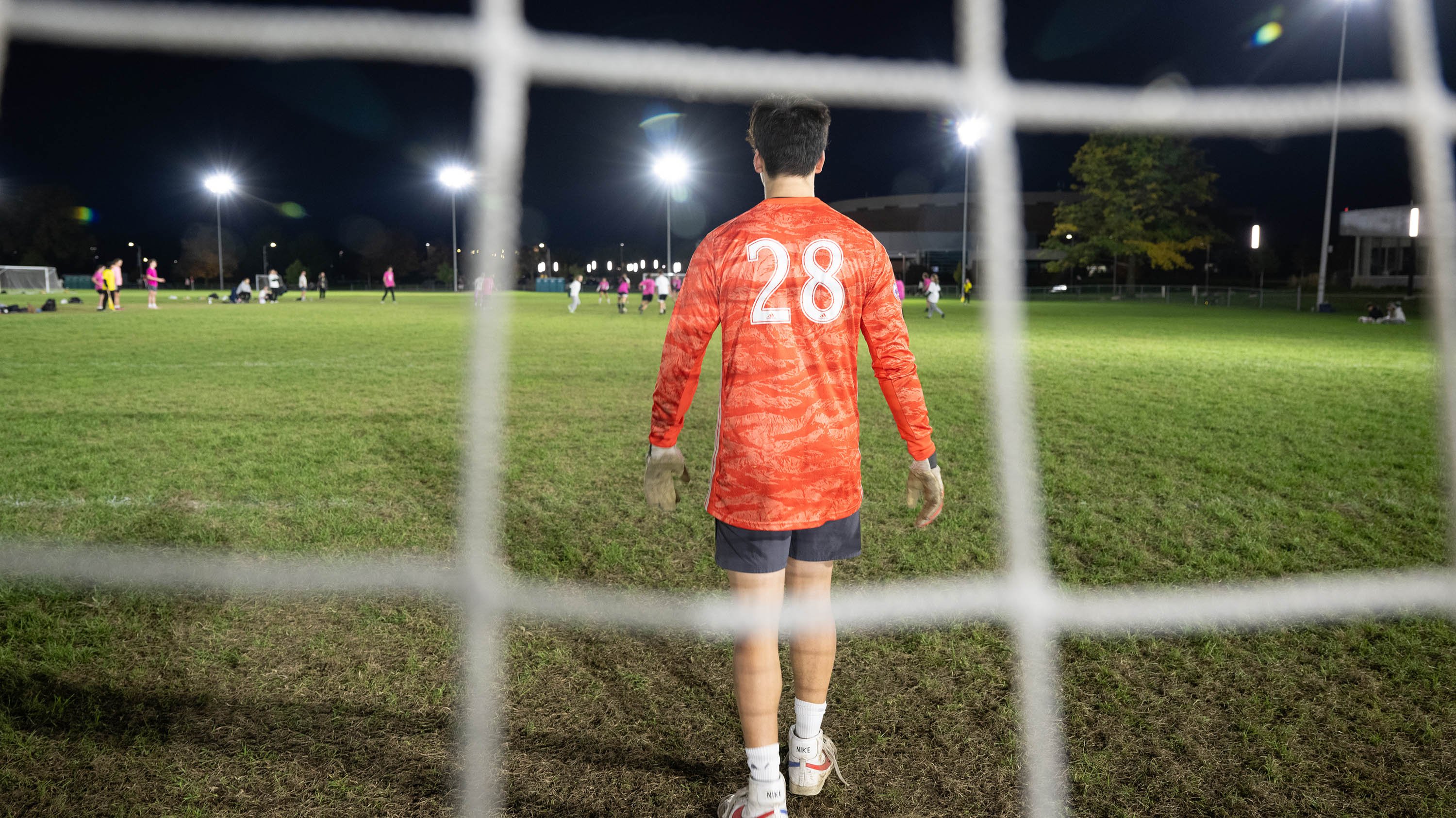 Intramural soccer goalie standing behind net, facing field