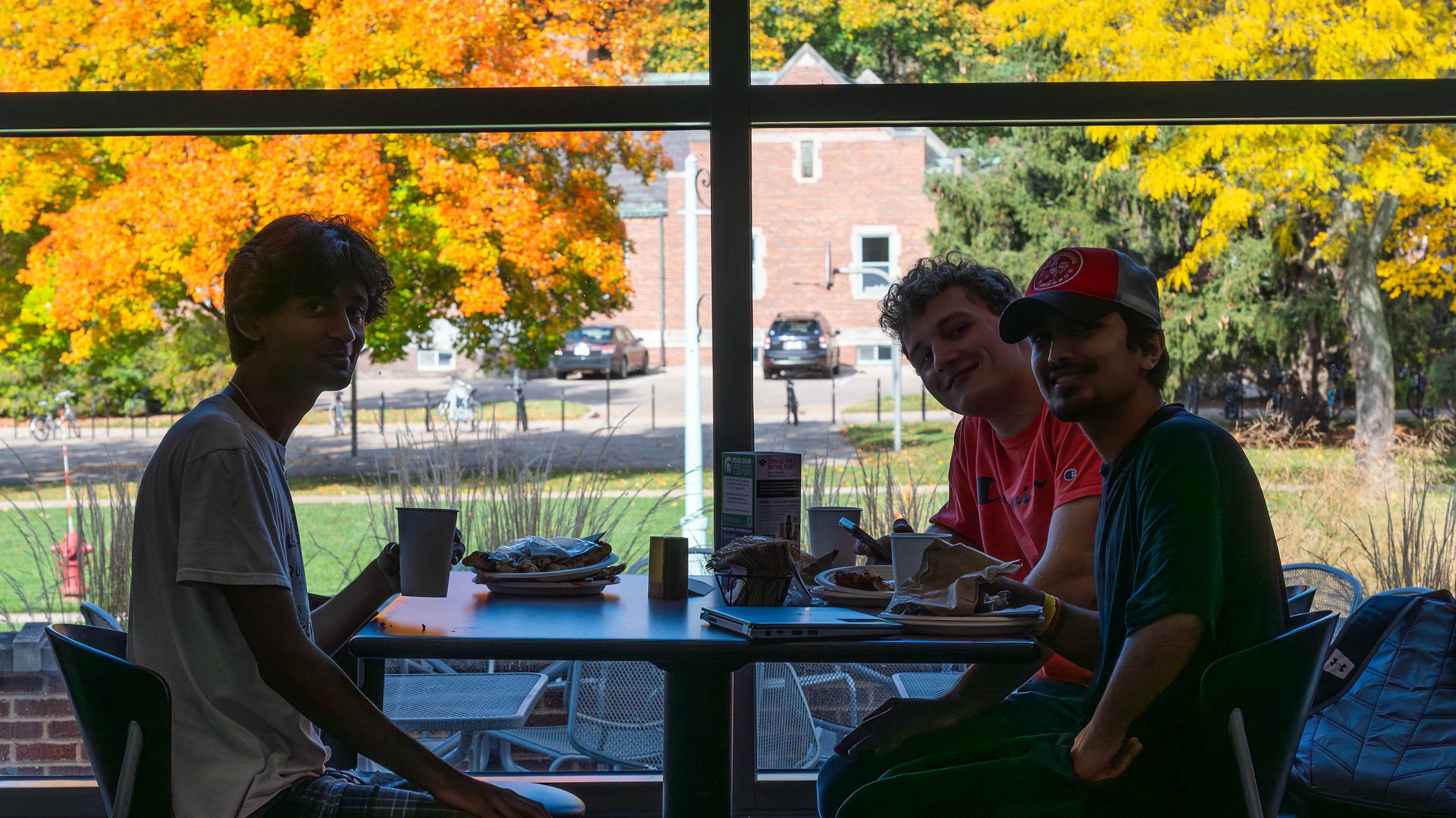 Three students eating at table in dining hall