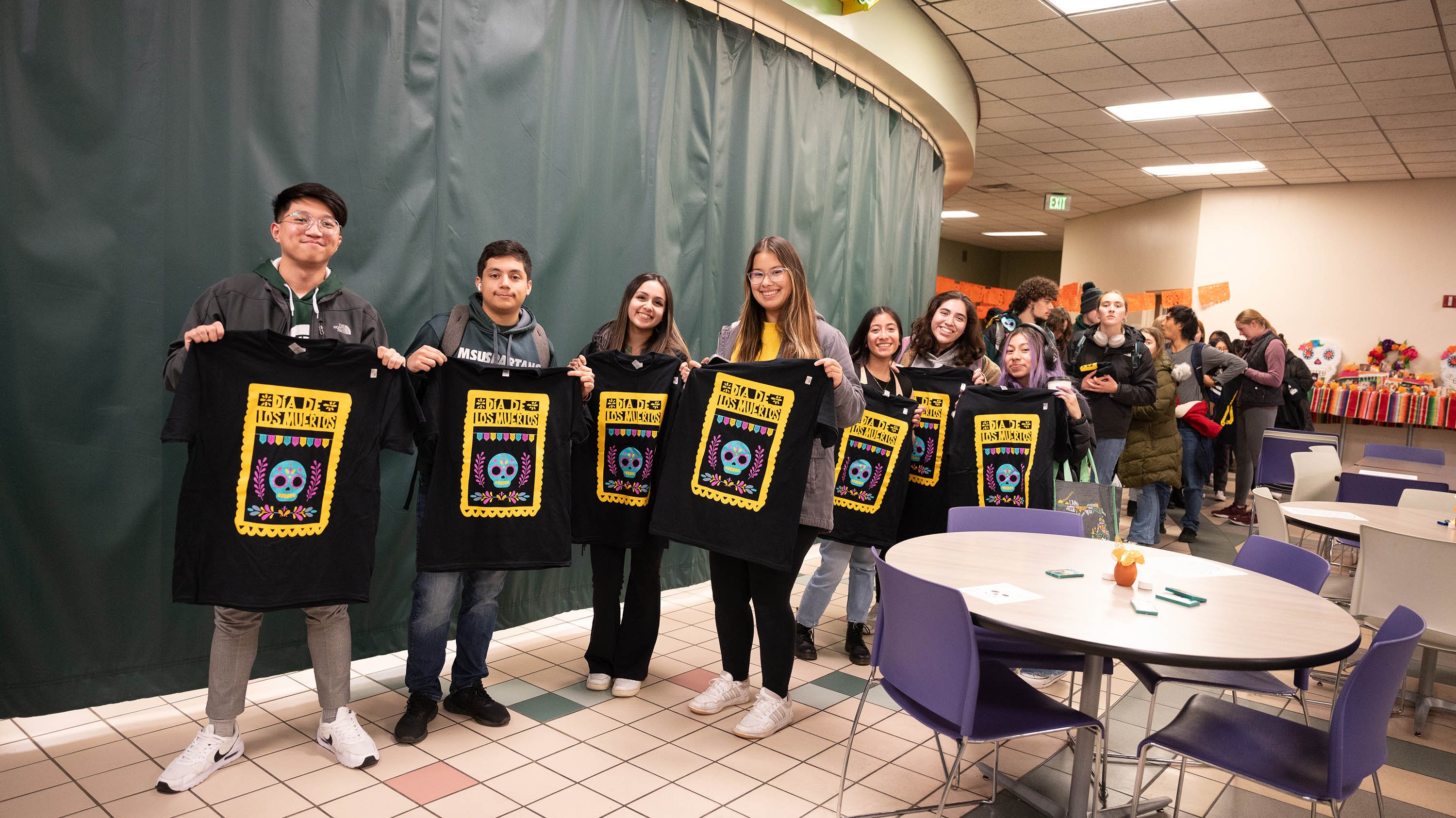 Students holding Dia de los Muertos t-shirts