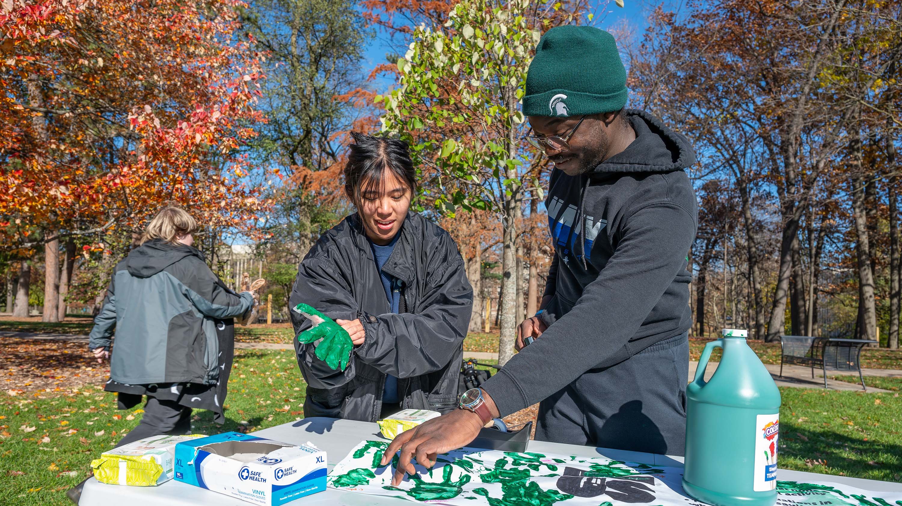 Students placing green handprints on a banner for It's On Us event