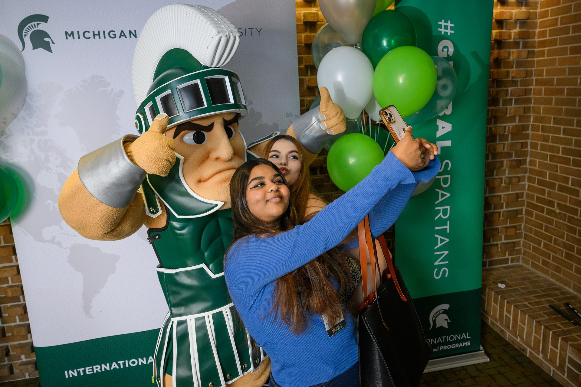 International students pose for a selfie with Sparty.