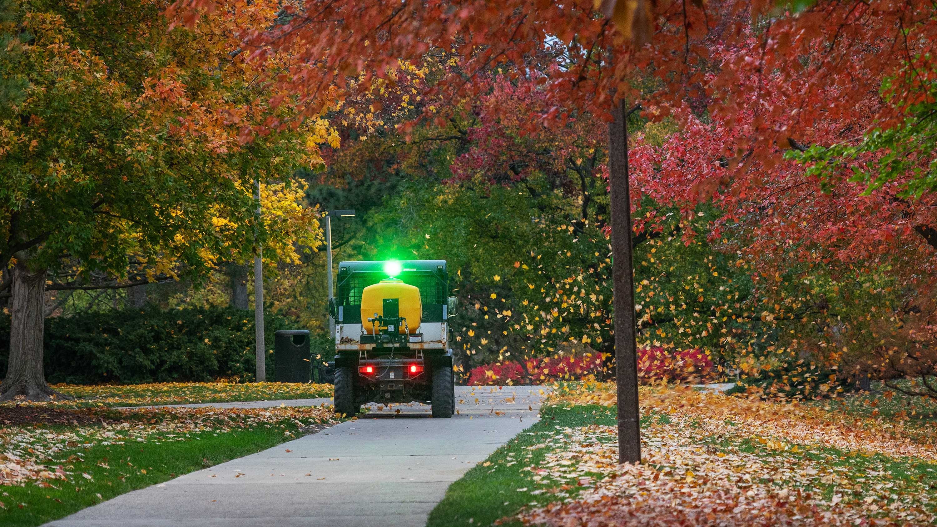 Landscape Services truck blowing leaves off of campus path