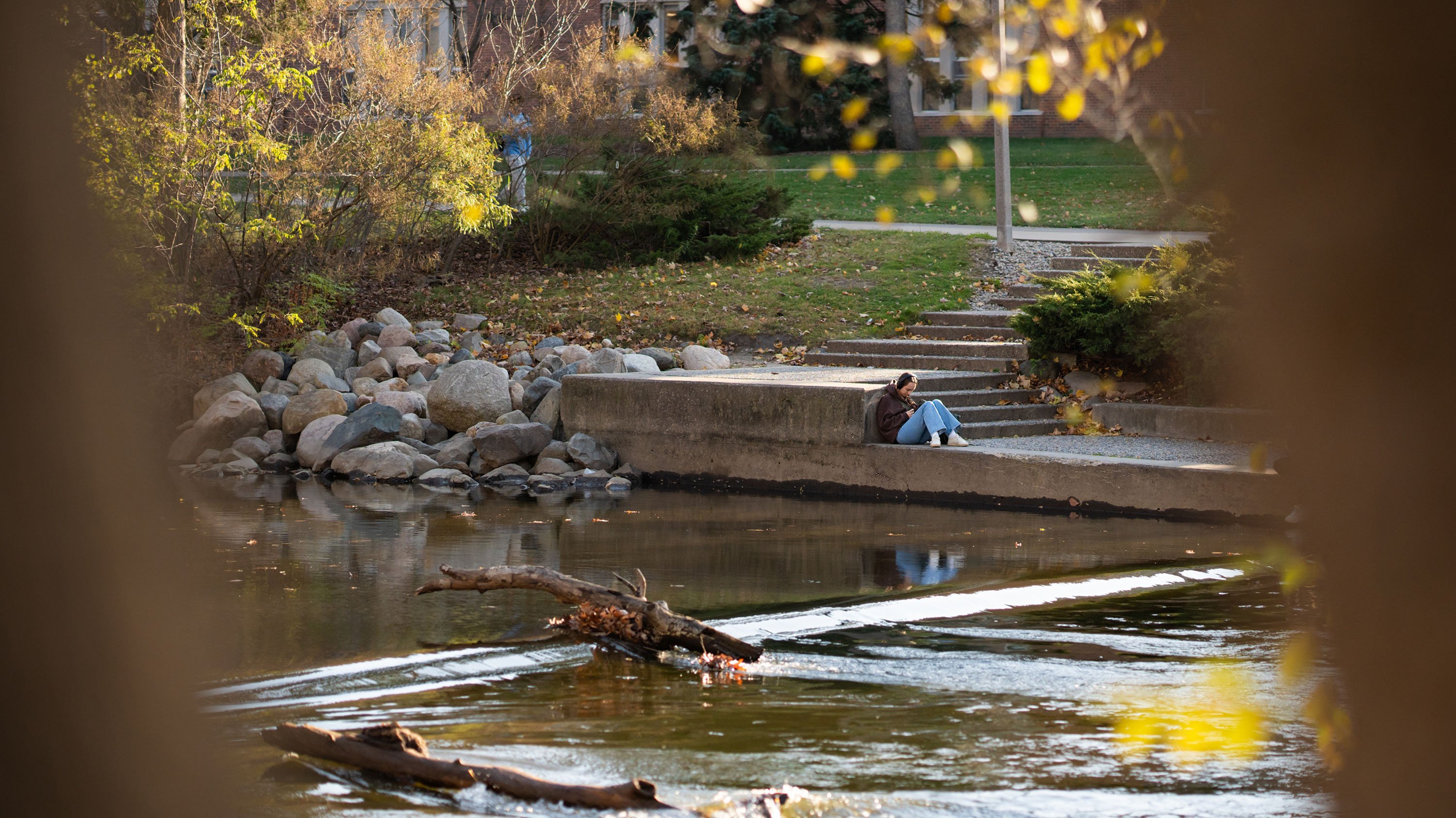 Student studying across the Red Cedar