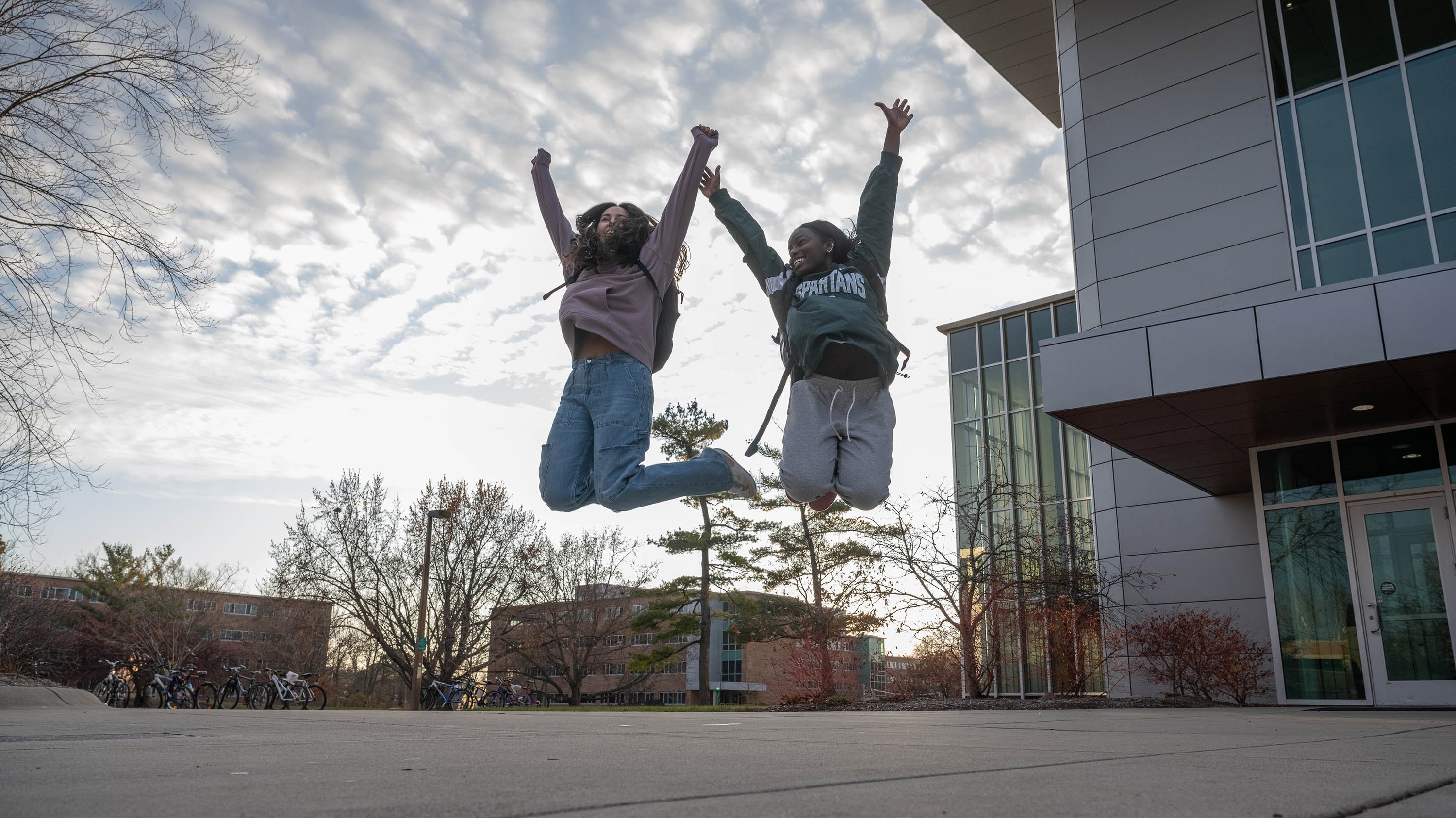 Two students jumping in front of Brody Square
