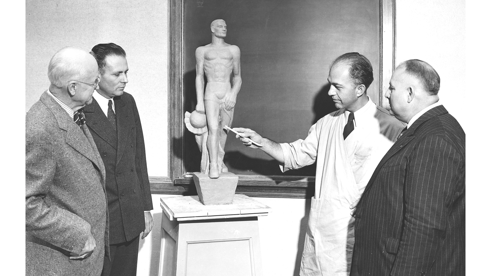 Circa 1943, before the Spartan Statue was completed, Leonard Jungwirth showed University Presdient John Hannah (second from left) and others a model of the sculpture. 