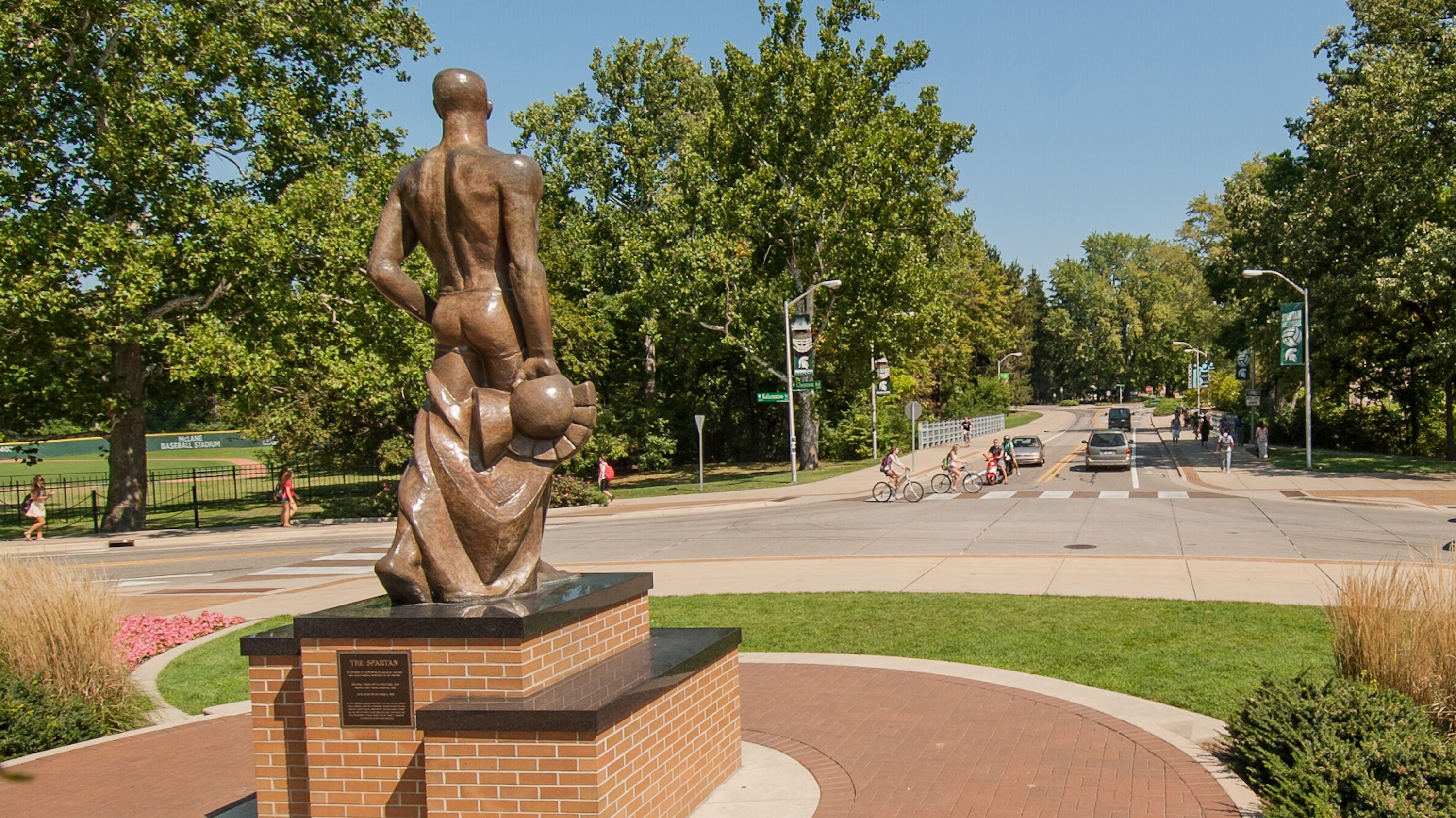 A view of the Spartan Statue from behind, as it glances out over the intersection just south of the Red Cedar River.