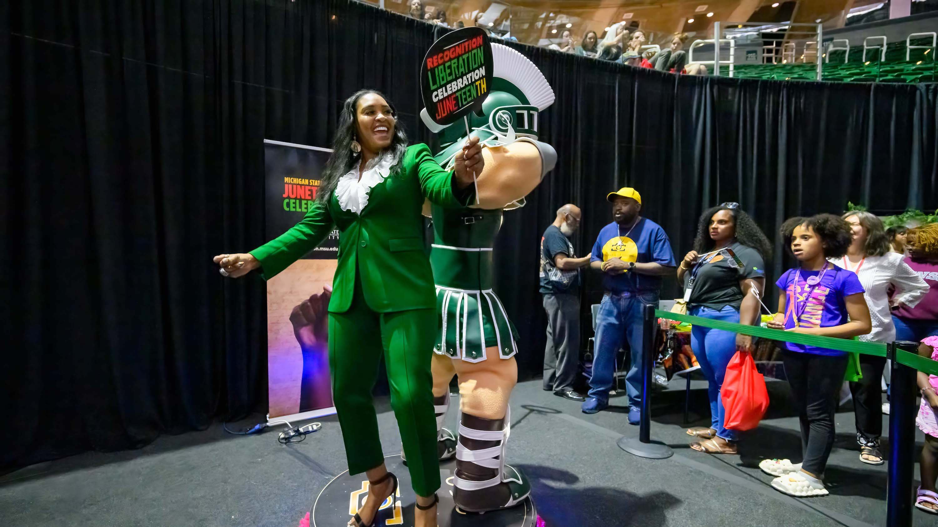 Trustee Chair Rema Vassar, Ph.D., jumps on the 360-photo booth with Sparty at the MSU Juneteenth Celebration